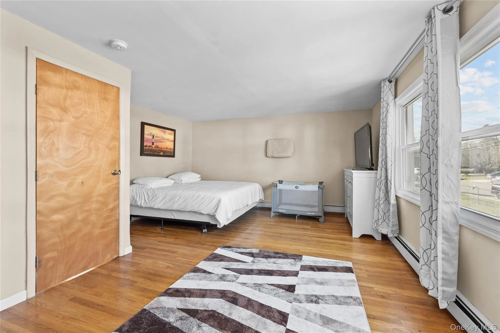 Bedroom featuring light wood-style floors, a baseboard heating unit, and a baseboard radiator Bedroom featuring light wood-style floors, a baseboard heating unit, and a baseboard radiator