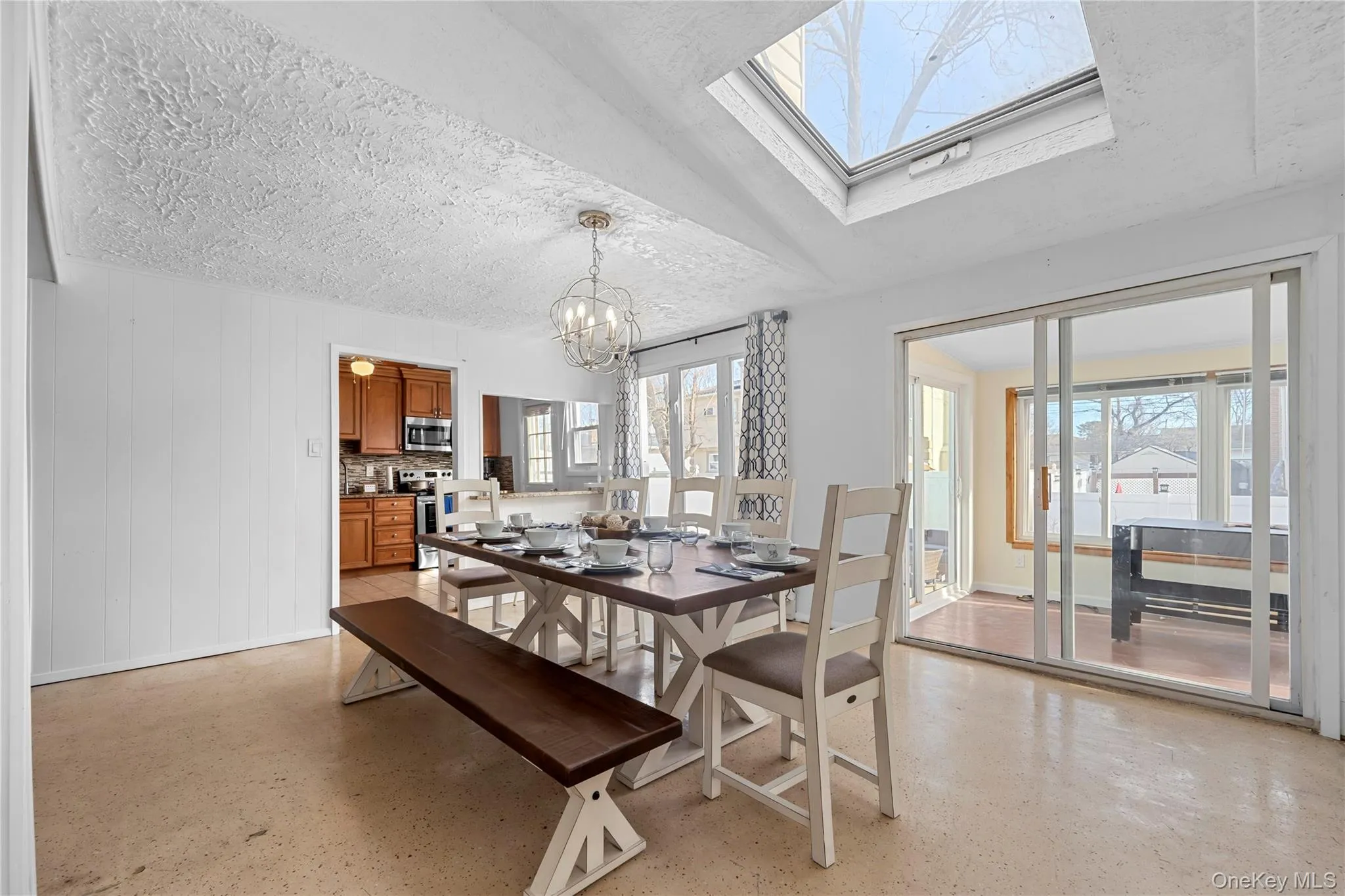 Dining space featuring a skylight, a chandelier, and a textured ceiling Dining space featuring a skylight, a chandelier, and a textured ceiling