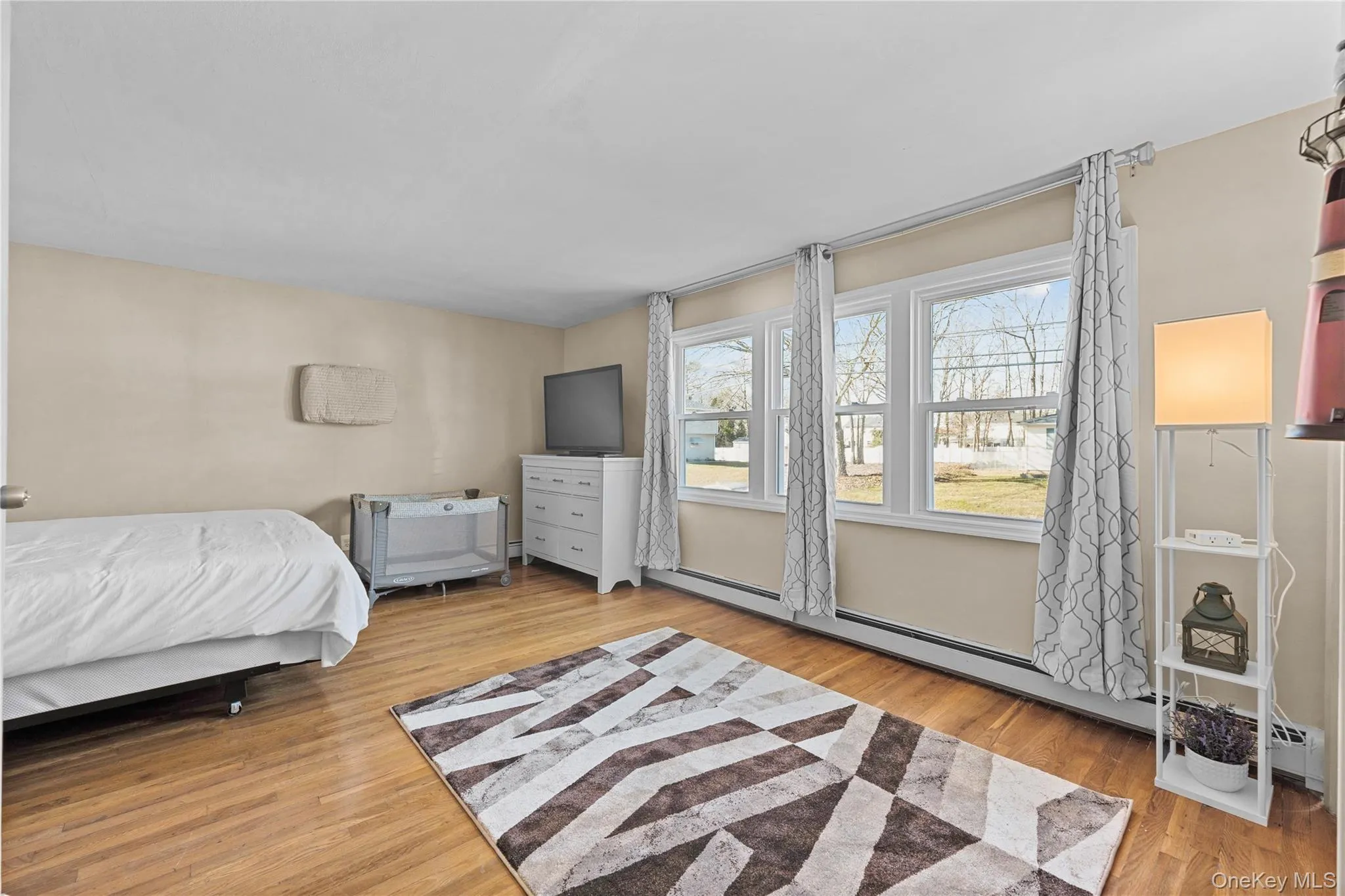 Bedroom featuring light wood-style flooring and a baseboard radiator Bedroom featuring light wood-style flooring and a baseboard radiator