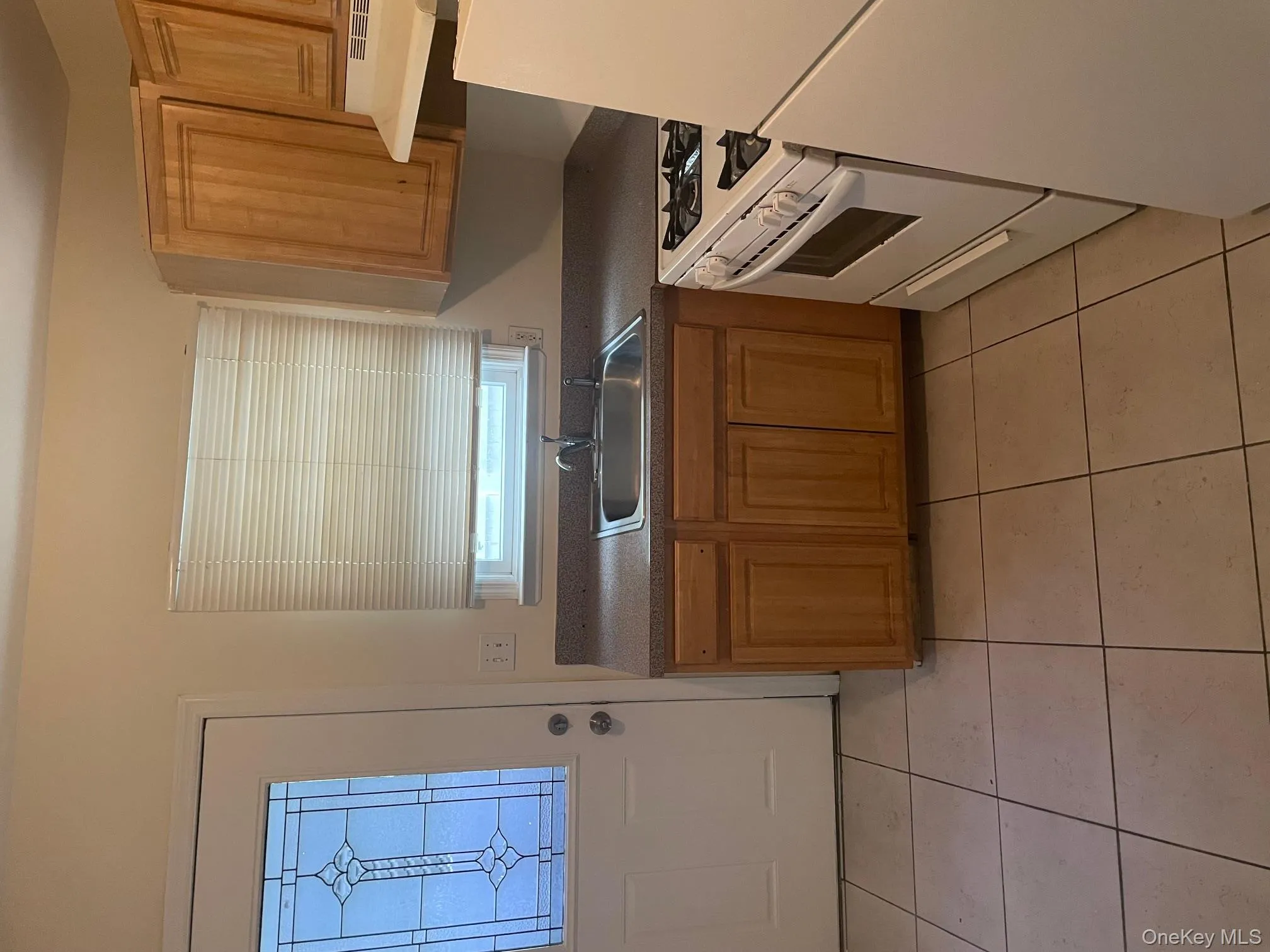 Kitchen featuring dark countertops, fridge, stove, and light tile patterned floors Kitchen featuring dark countertops, fridge, stove, and light tile patterned floors