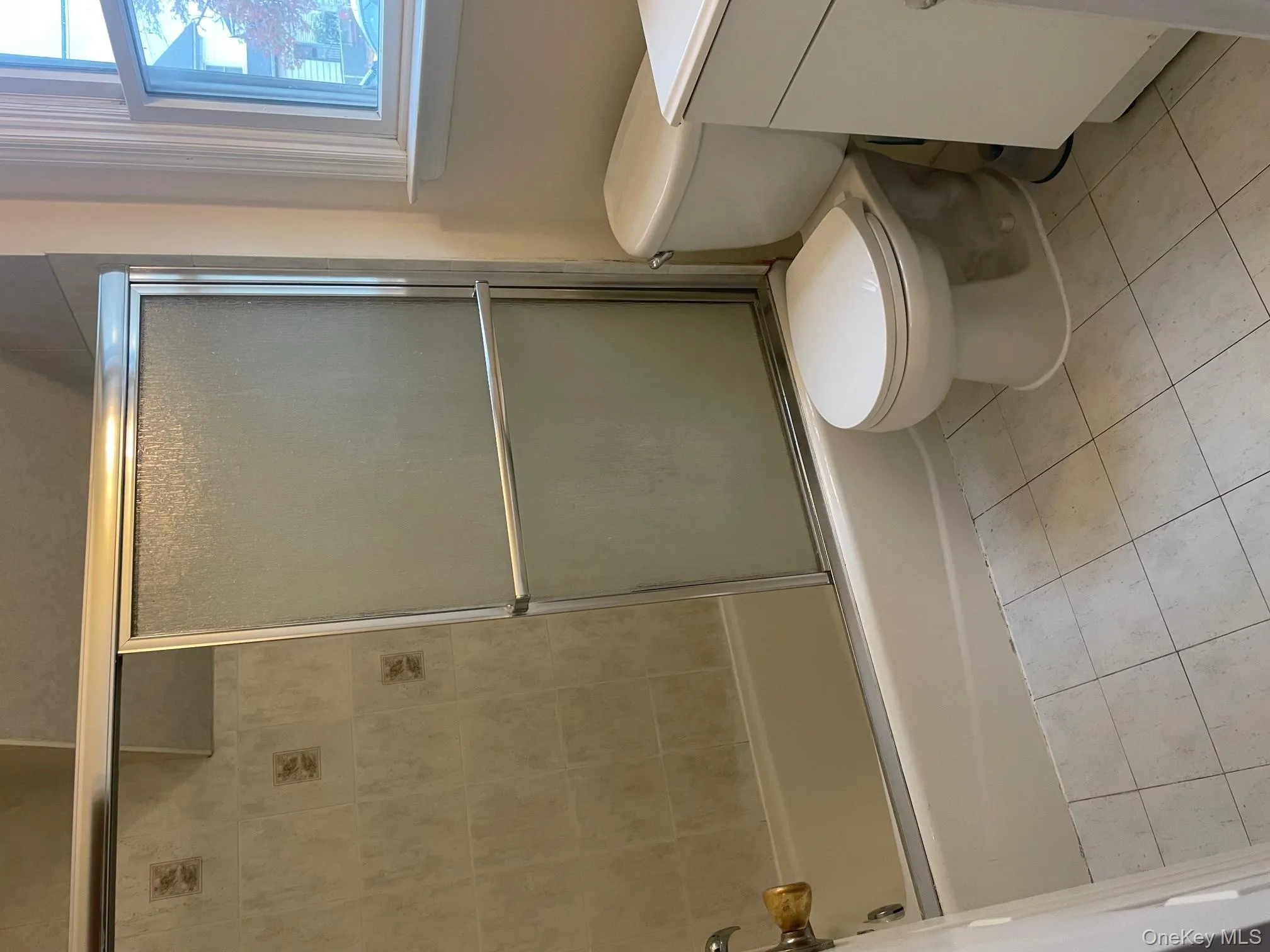 Bathroom featuring vanity, shower / bath combination with glass door, and light tile patterned floors Bathroom featuring vanity, shower / bath combination with glass door, and light tile patterned floors