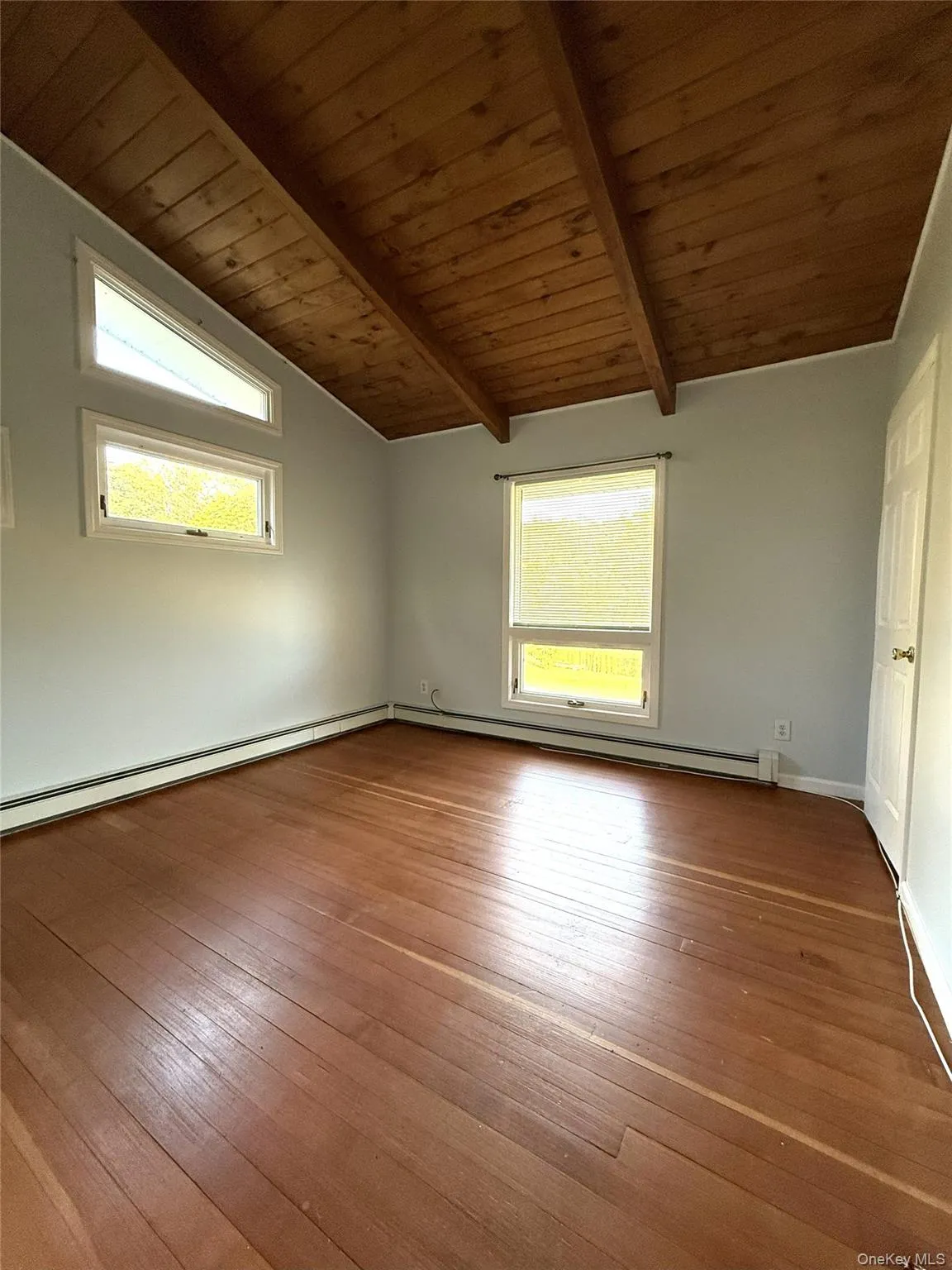 Empty room featuring wood ceiling, plenty of natural light, light wood-type flooring, and a baseboard radiator Empty room featuring wood ceiling, plenty of natural light, light wood-type flooring, and a baseboard radiator