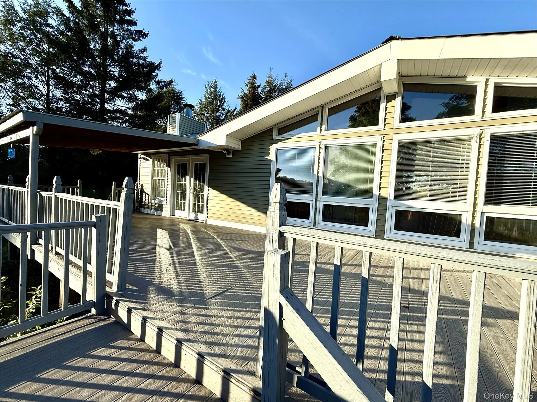 View of side of property featuring a chimney, a deck, and french doors View of side of property featuring a chimney, a deck, and french doors