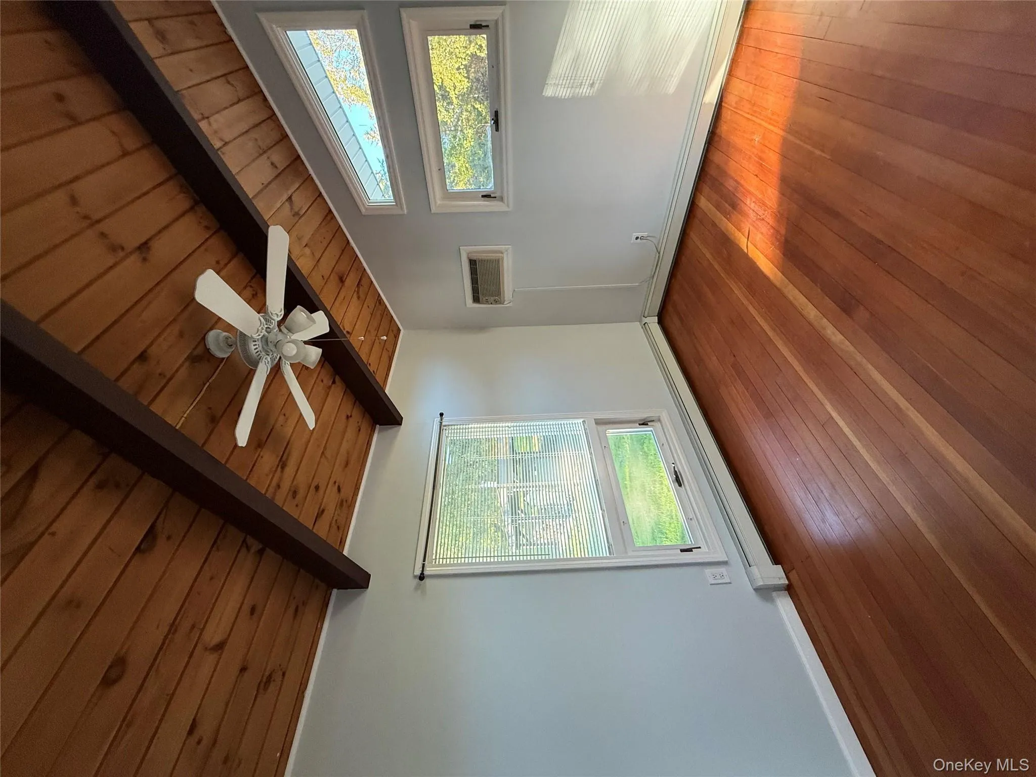 Unfurnished room with wood-type flooring, wood ceiling, a ceiling fan, a baseboard radiator, and a wall mounted AC Unfurnished room with wood-type flooring, wood ceiling, a ceiling fan, a baseboard radiator, and a wall mounted AC