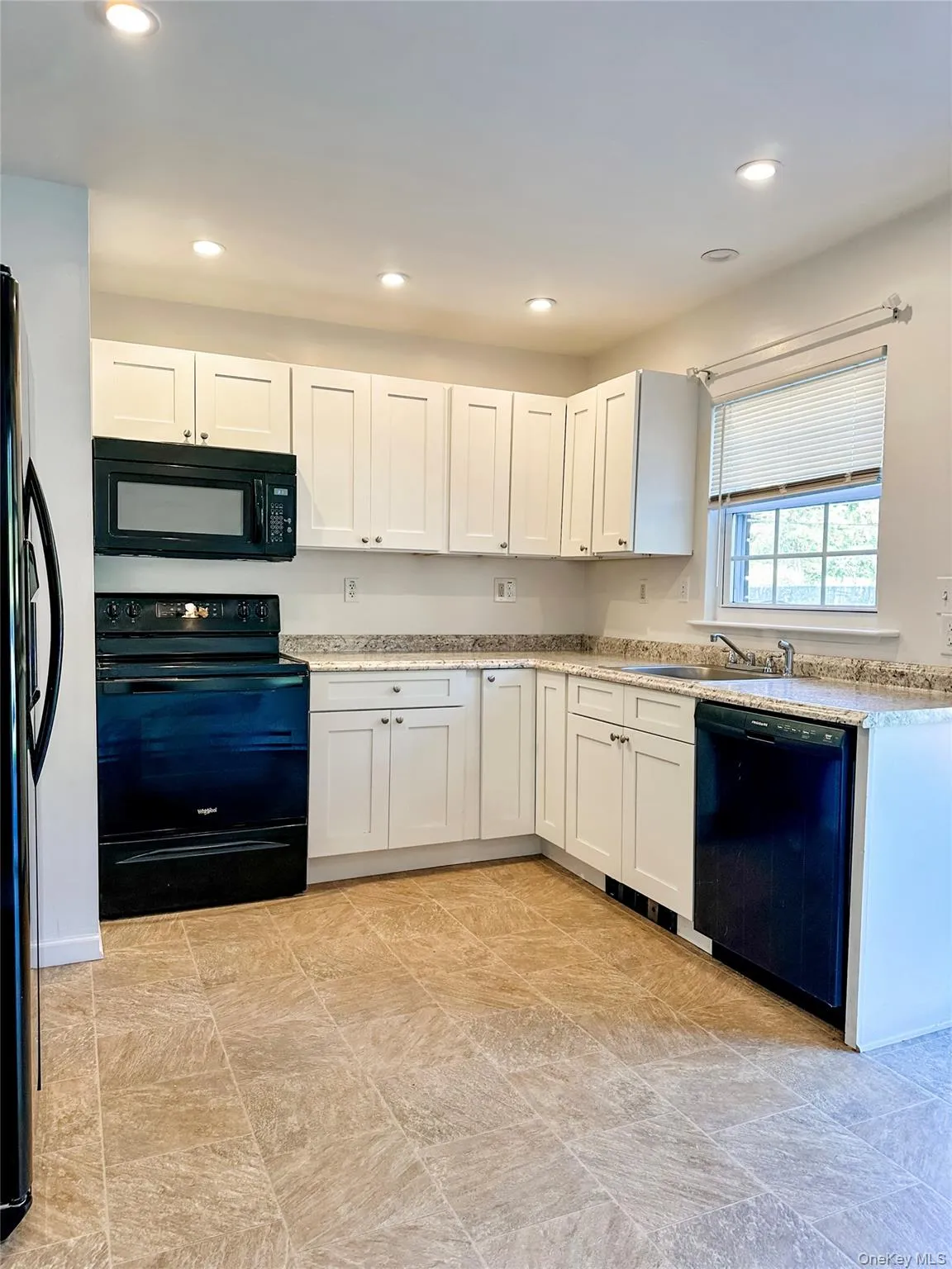 Kitchen featuring black appliances, white cabinets, recessed lighting, and light stone countertops Kitchen featuring black appliances, white cabinets, recessed lighting, and light stone countertops