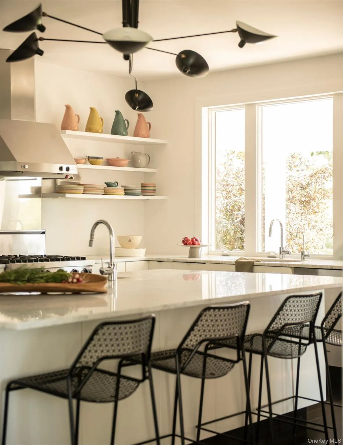 Bar area with light stone counters, wall chimney range hood, open shelves, and white cabinetry Bar area with light stone counters, wall chimney range hood, open shelves, and white cabinetry