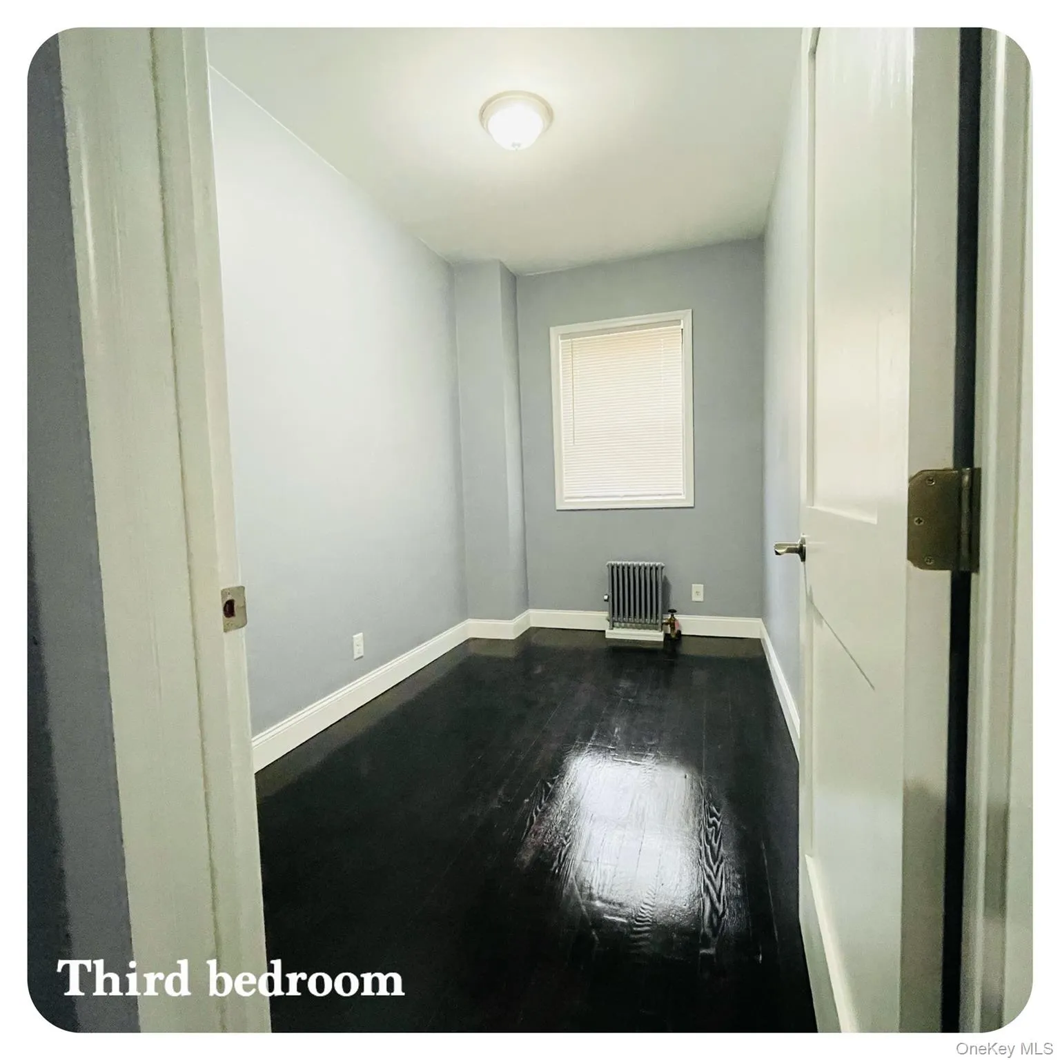 Third bedroom with wood flooring and radiator heating unit Third bedroom with wood flooring and radiator heating unit