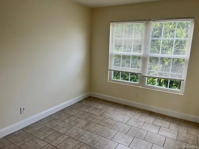 Unfurnished room with baseboards and light tile patterned floors Unfurnished room with baseboards and light tile patterned floors