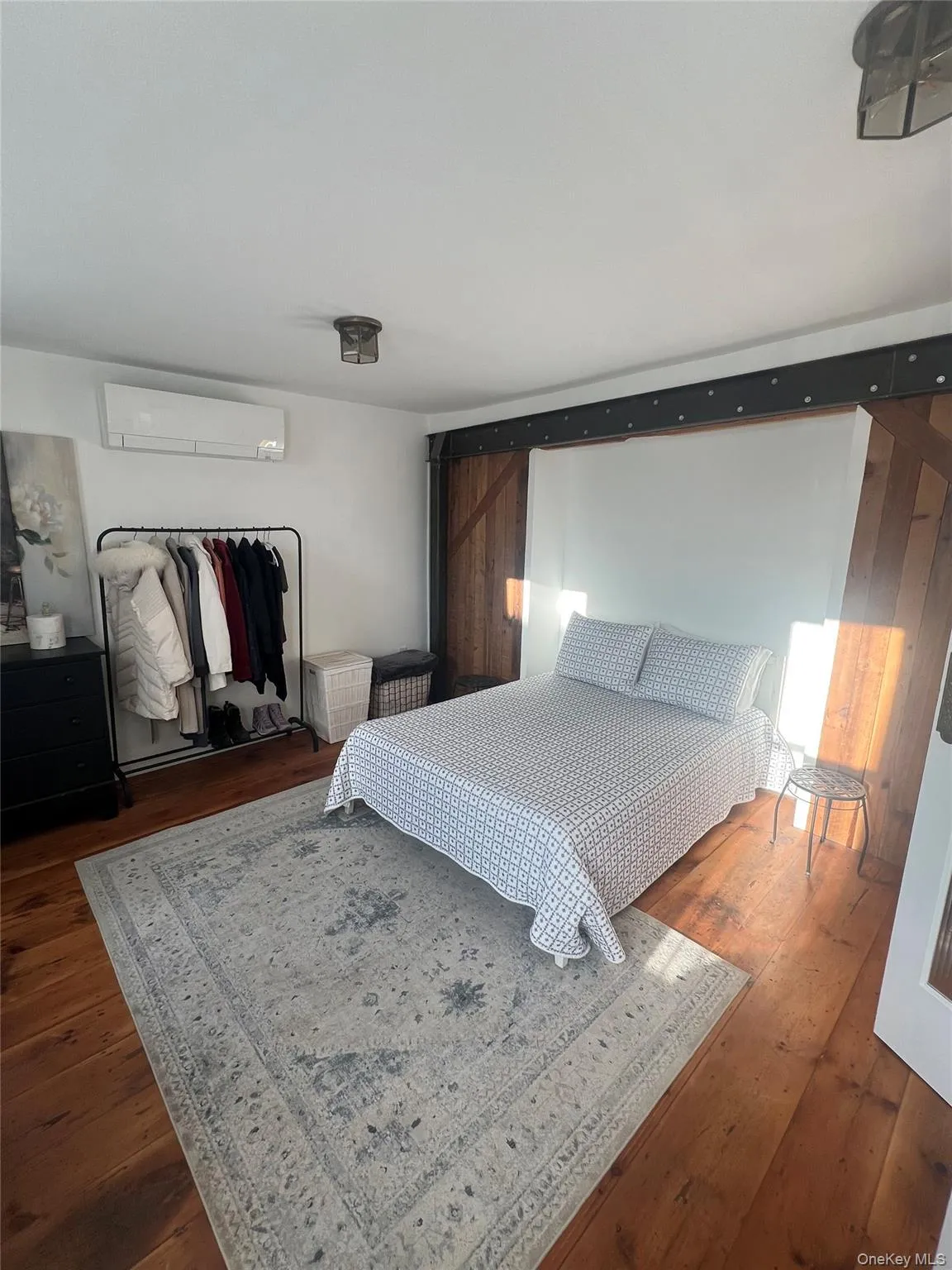 Bedroom with hardwood floors, a split air conditioner, and a baseboard radiator Bedroom with hardwood floors, a split air conditioner, and a baseboard radiator