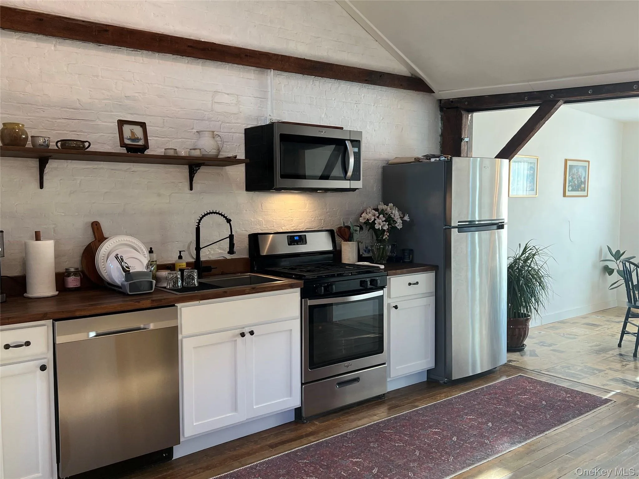 Kitchen featuring appliances with stainless steel finishes, white cabinetry, dark wood-style floors, and open shelves Kitchen featuring appliances with stainless steel finishes, white cabinetry, dark wood-style floors, and open shelves