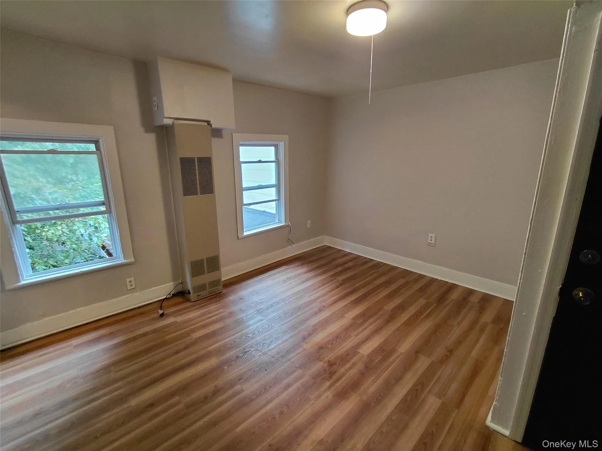 Unfurnished bedroom featuring light wood-type flooring and a heating unit Unfurnished bedroom featuring light wood-type flooring and a heating unit