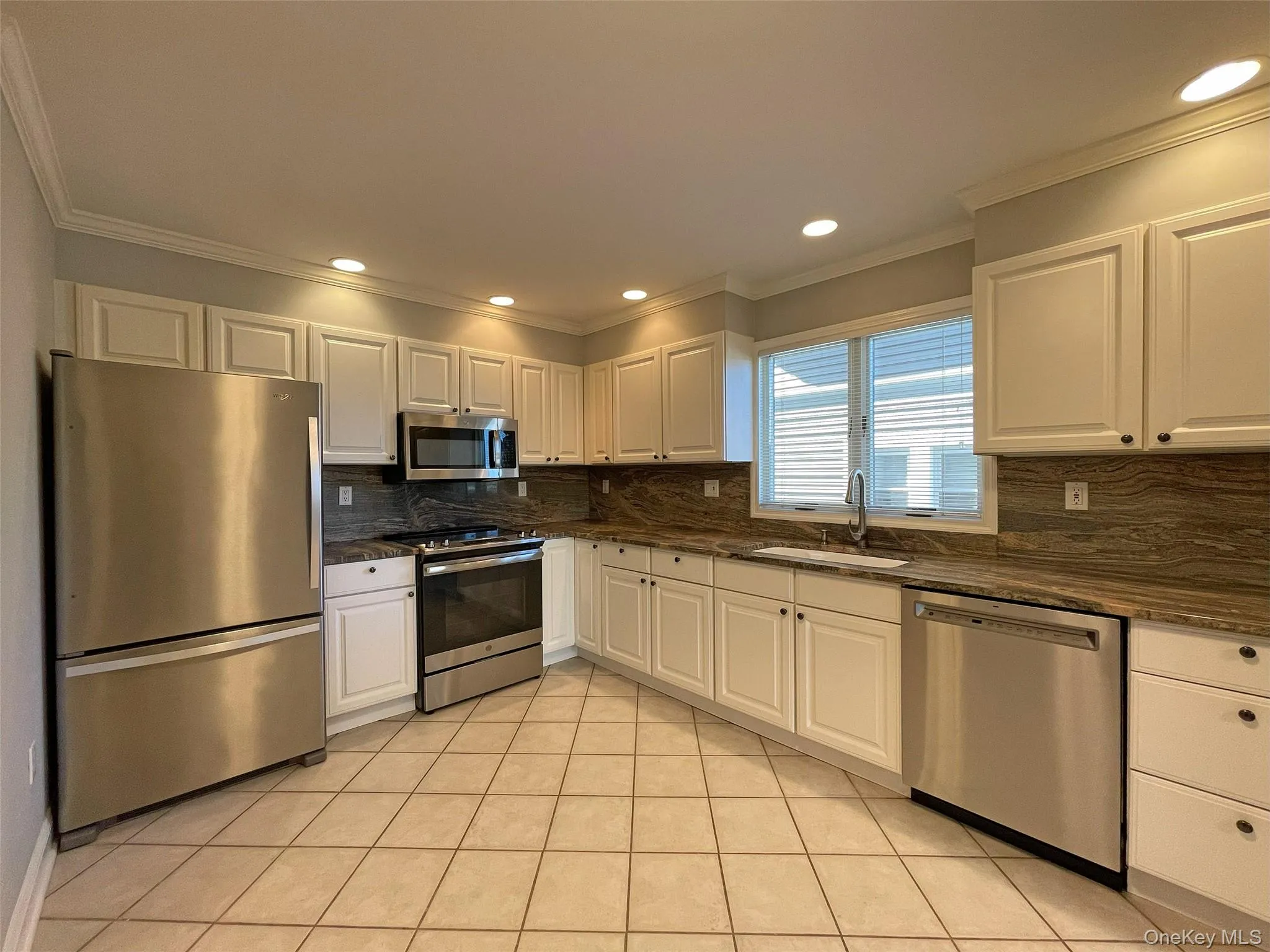 Kitchen featuring white cabinetry, stainless steel appliances, crown molding, tasteful backsplash, and recessed lighting Kitchen featuring white cabinetry, stainless steel appliances, crown molding, tasteful backsplash, and recessed lighting