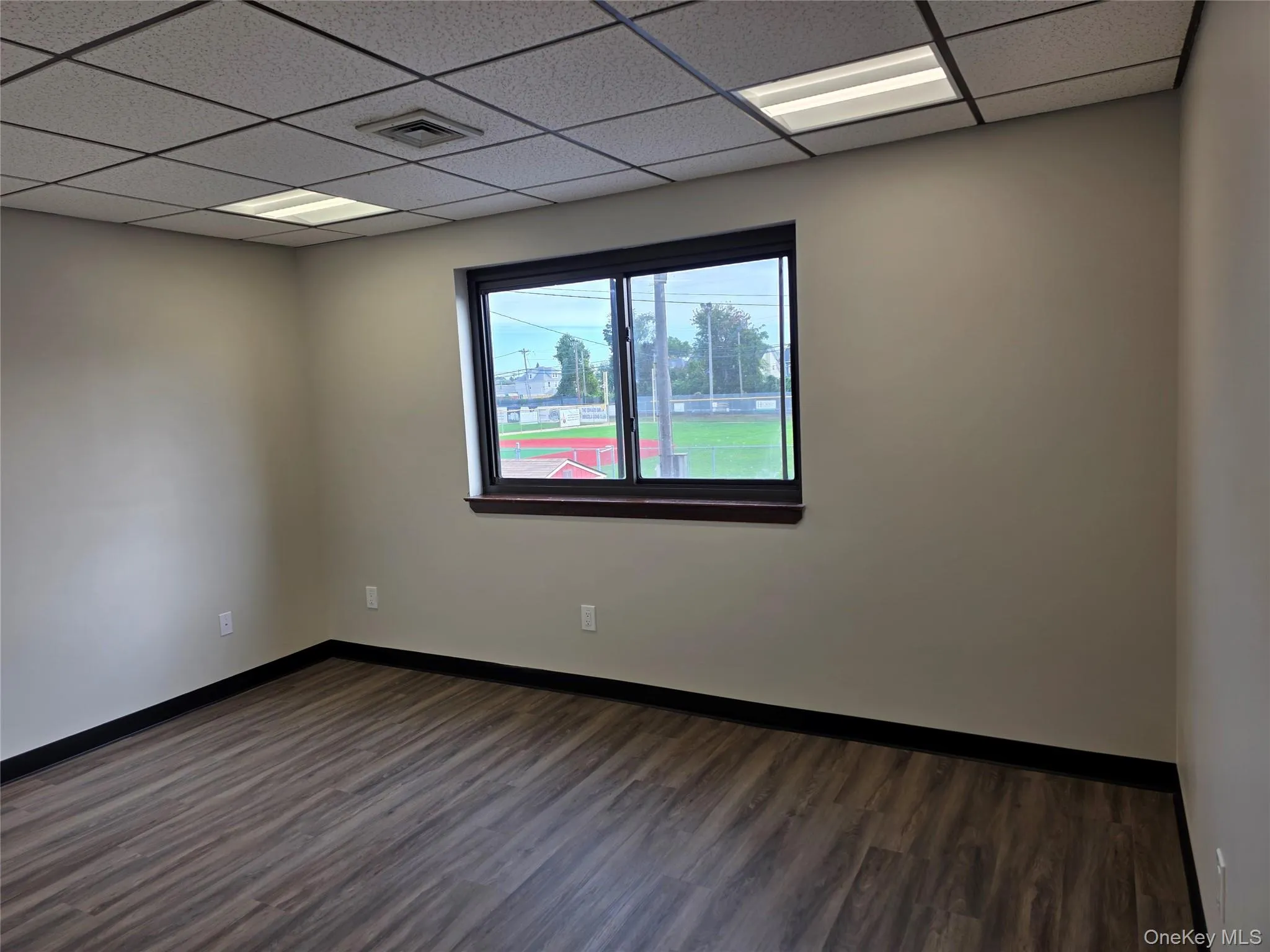 Unfurnished room featuring dark wood-type flooring and a paneled ceiling Unfurnished room featuring dark wood-type flooring and a paneled ceiling