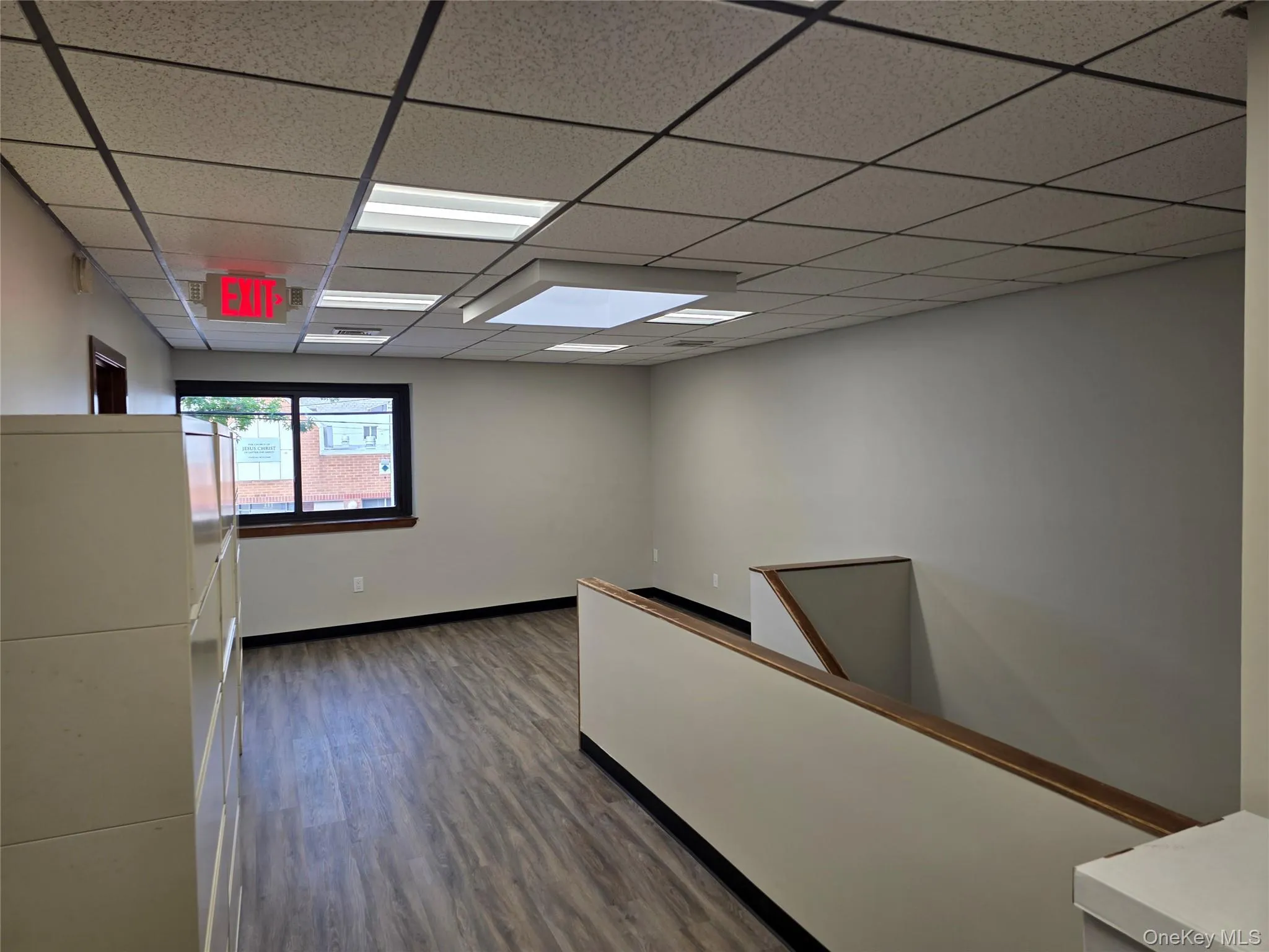 Empty room featuring a drop ceiling and dark wood-style floors Empty room featuring a drop ceiling and dark wood-style floors
