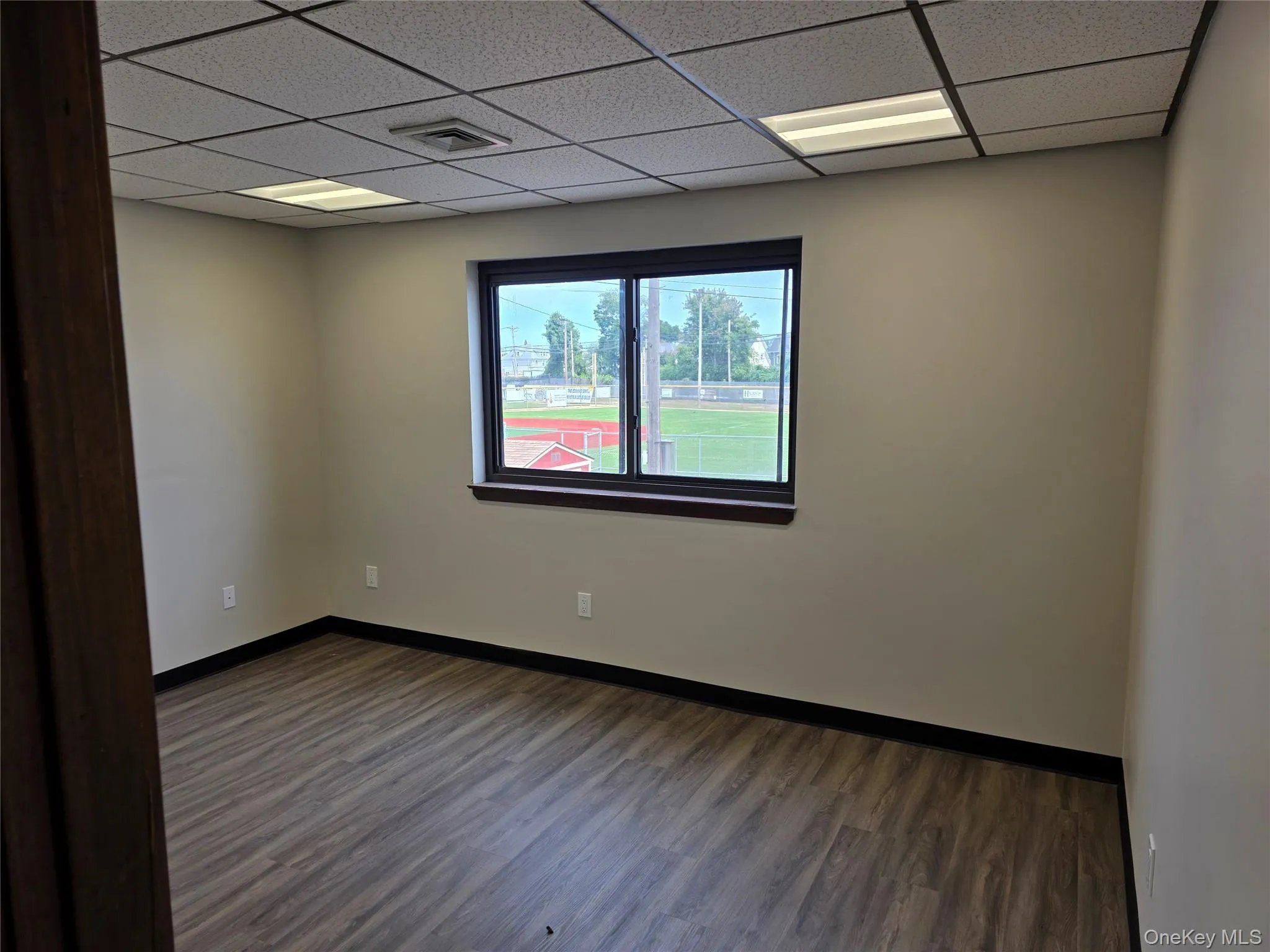Spare room featuring dark wood-type flooring and a paneled ceiling Spare room featuring dark wood-type flooring and a paneled ceiling