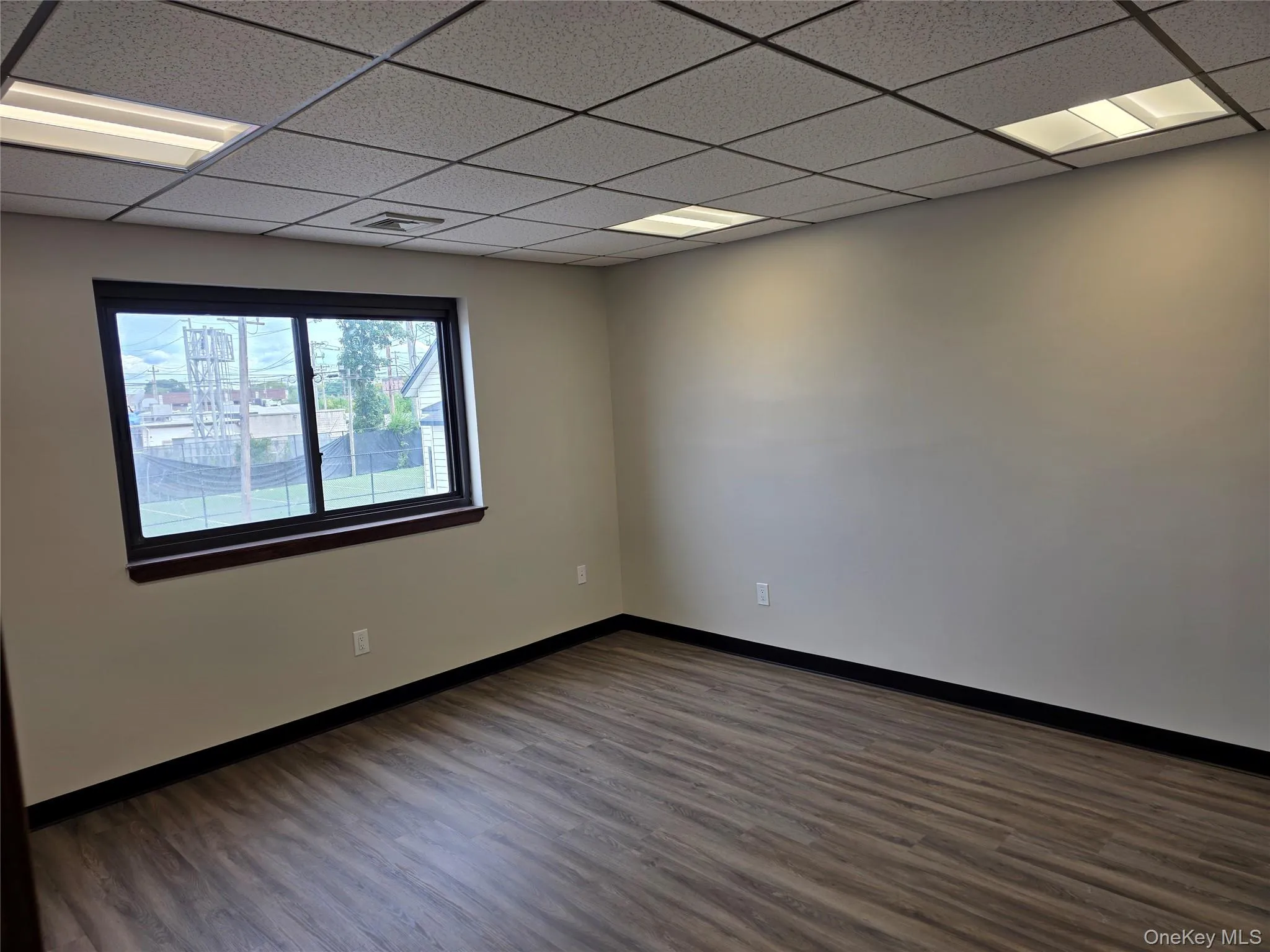 Spare room featuring dark wood-style flooring and a paneled ceiling Spare room featuring dark wood-style flooring and a paneled ceiling