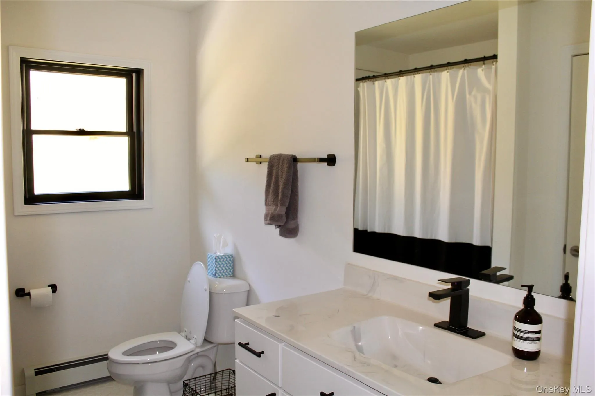 Full bath featuring baseboard heating, vanity, and a shower with curtain Full bath featuring baseboard heating, vanity, and a shower with curtain