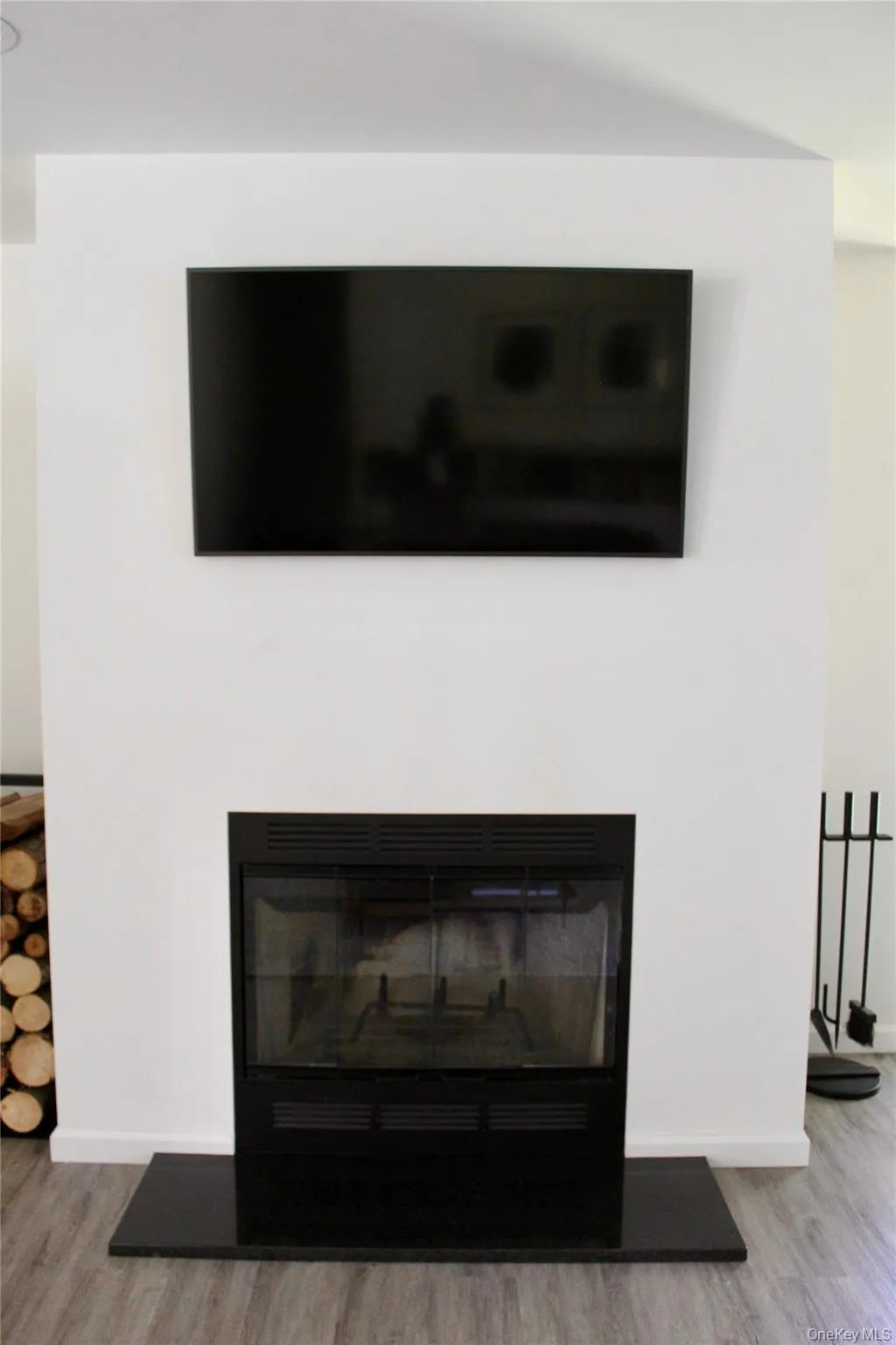 Detailed view of a glass covered fireplace and wood finished floors Detailed view of a glass covered fireplace and wood finished floors