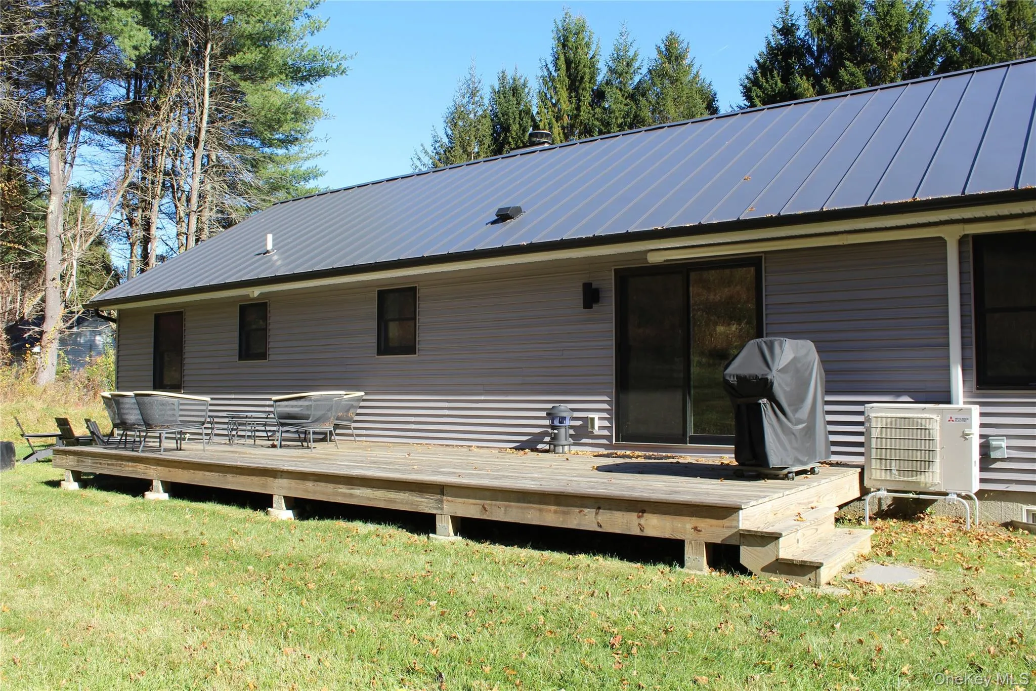 Back of property with a metal roof, a yard, and a deck Back of property with a metal roof, a yard, and a deck