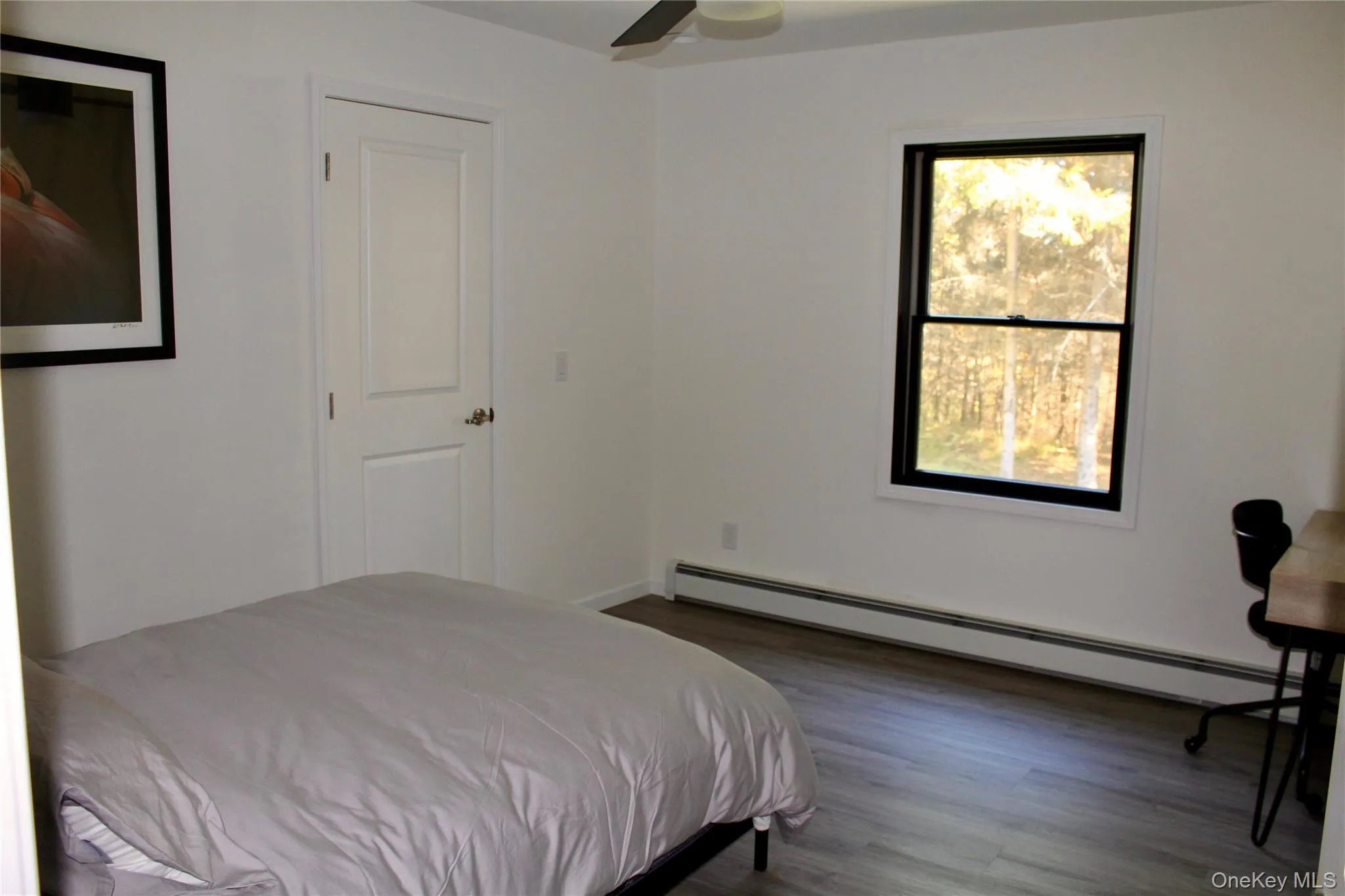 Bedroom with baseboard heating, dark wood-style floors, and a ceiling fan Bedroom with baseboard heating, dark wood-style floors, and a ceiling fan