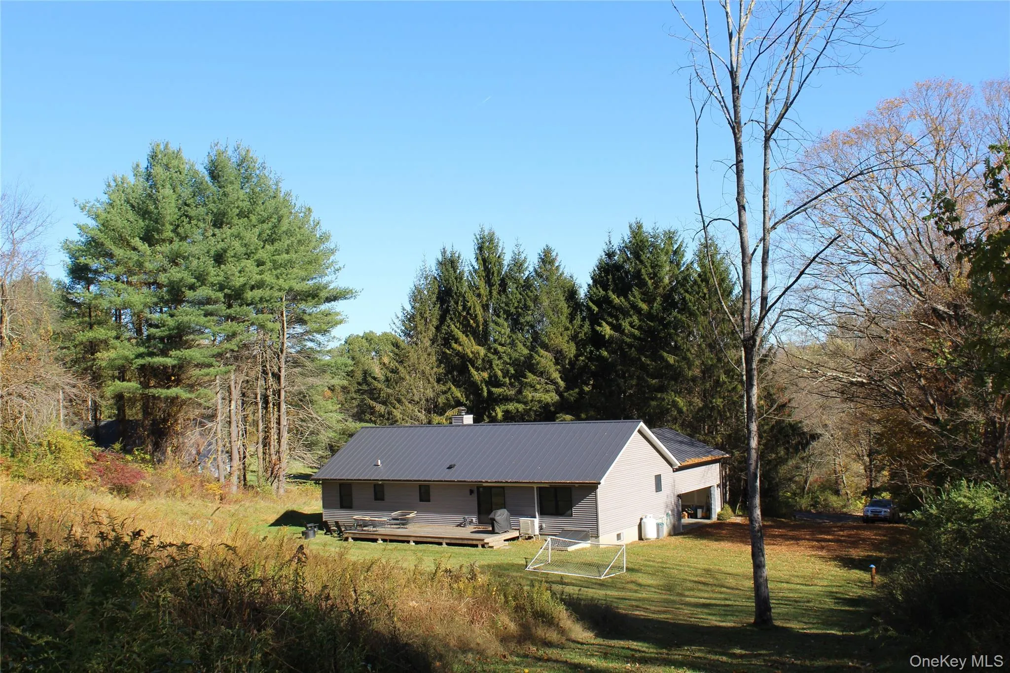 Back of property with a metal roof, a chimney, a yard, and a view of trees Back of property with a metal roof, a chimney, a yard, and a view of trees