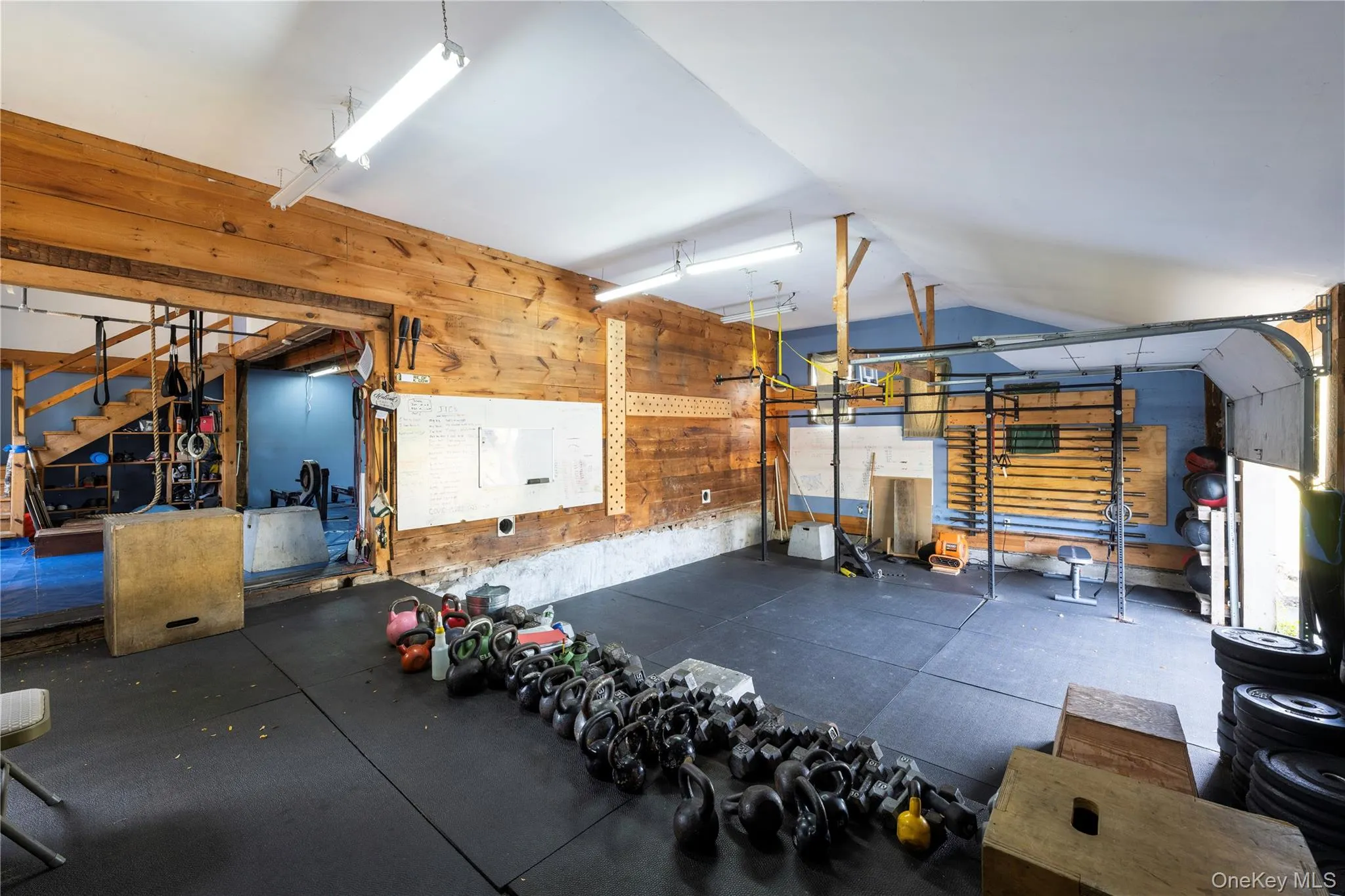 Workout room with a garage, wooden walls, and rubber floors Workout room with a garage, wooden walls, and rubber floors