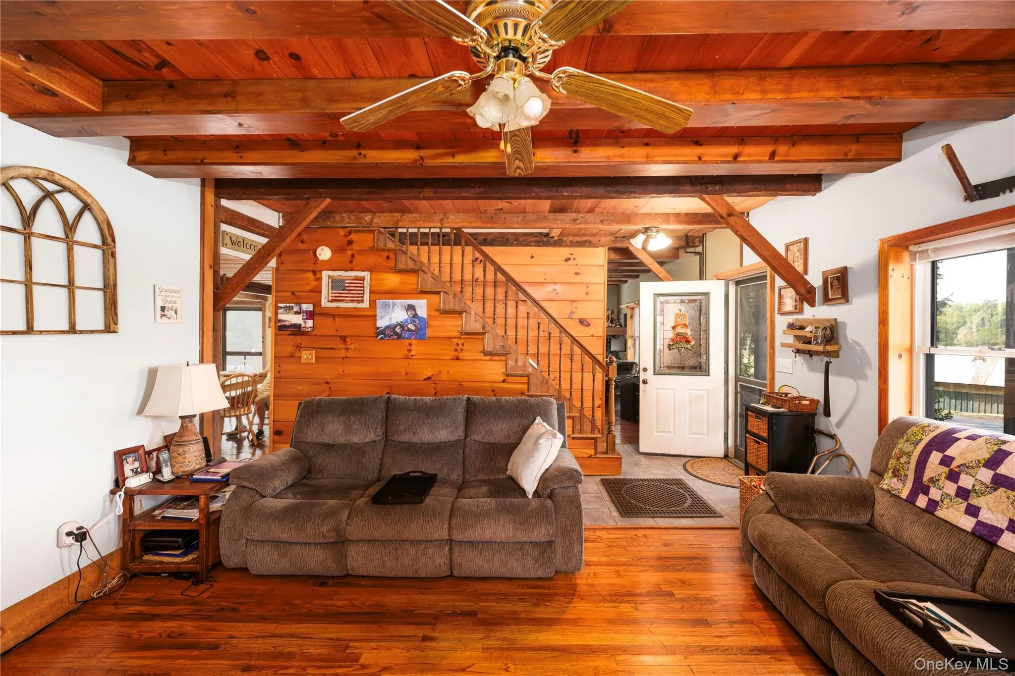 Living room featuring wood walls, wood finished floors, stairway, a wood ceiling with exposed beams, and ceiling fan Living room featuring wood walls, wood finished floors, stairway, a wood ceiling with exposed beams, and ceiling fan