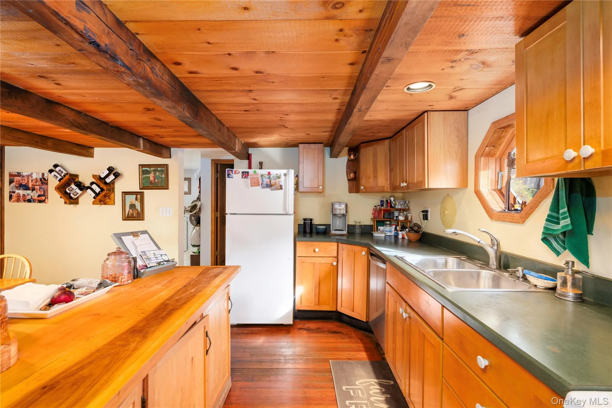 Kitchen with freestanding refrigerator, dark wood-type flooring, wood counters, stainless steel dishwasher, and brown cabinets Kitchen with freestanding refrigerator, dark wood-type flooring, wood counters, stainless steel dishwasher, and brown cabinets