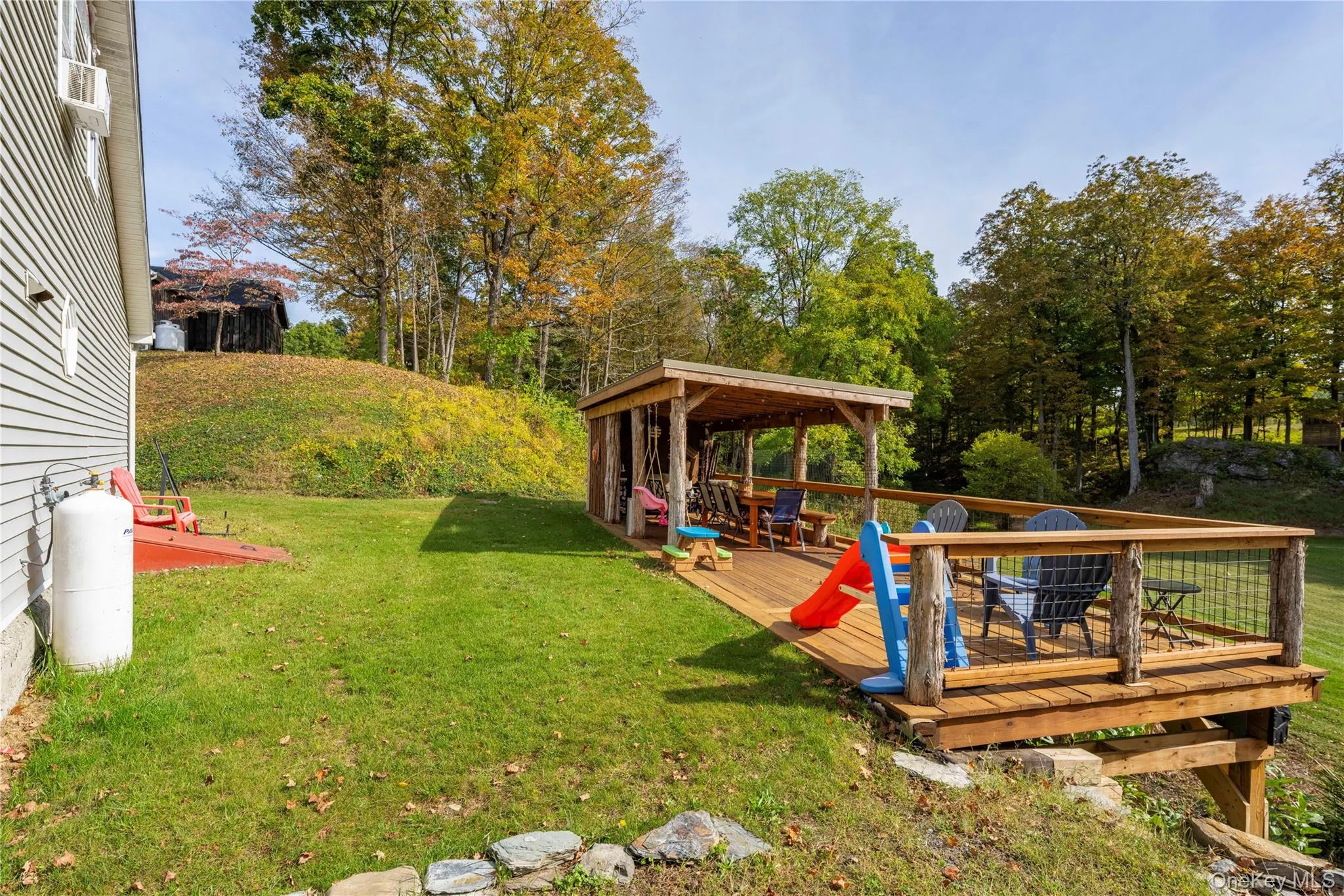 View of grassy yard with a wooden deck and view of wooded area View of grassy yard with a wooden deck and view of wooded area