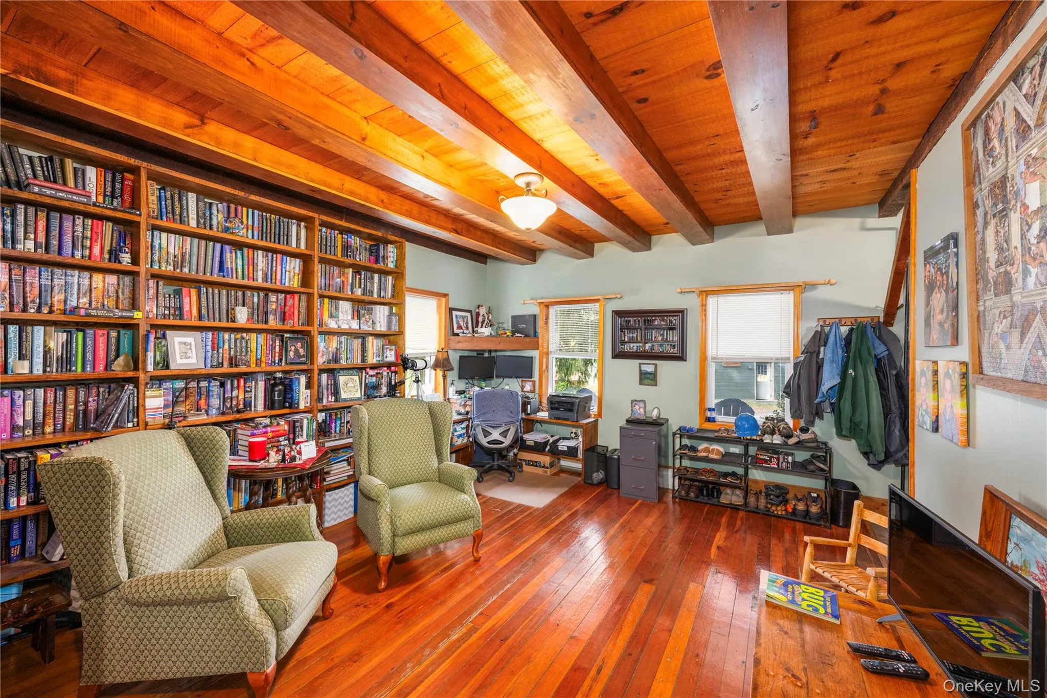 Sitting room with hardwood / wood-style floors, an office area, a wood ceiling with exposed beams, and wall of books Sitting room with hardwood / wood-style floors, an office area, a wood ceiling with exposed beams, and wall of books