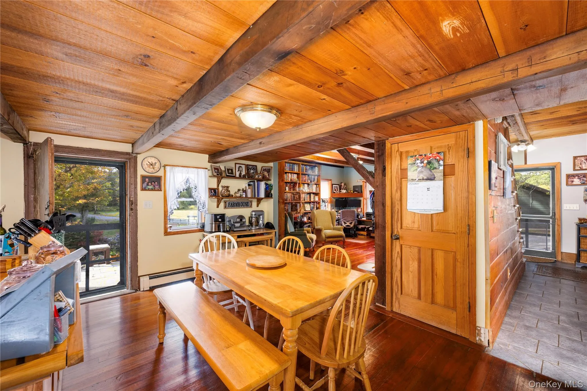 Dining area featuring hardwood / wood-style floors, baseboard heating, and a wooden ceiling with exposed beams Dining area featuring hardwood / wood-style floors, baseboard heating, and a wooden ceiling with exposed beams