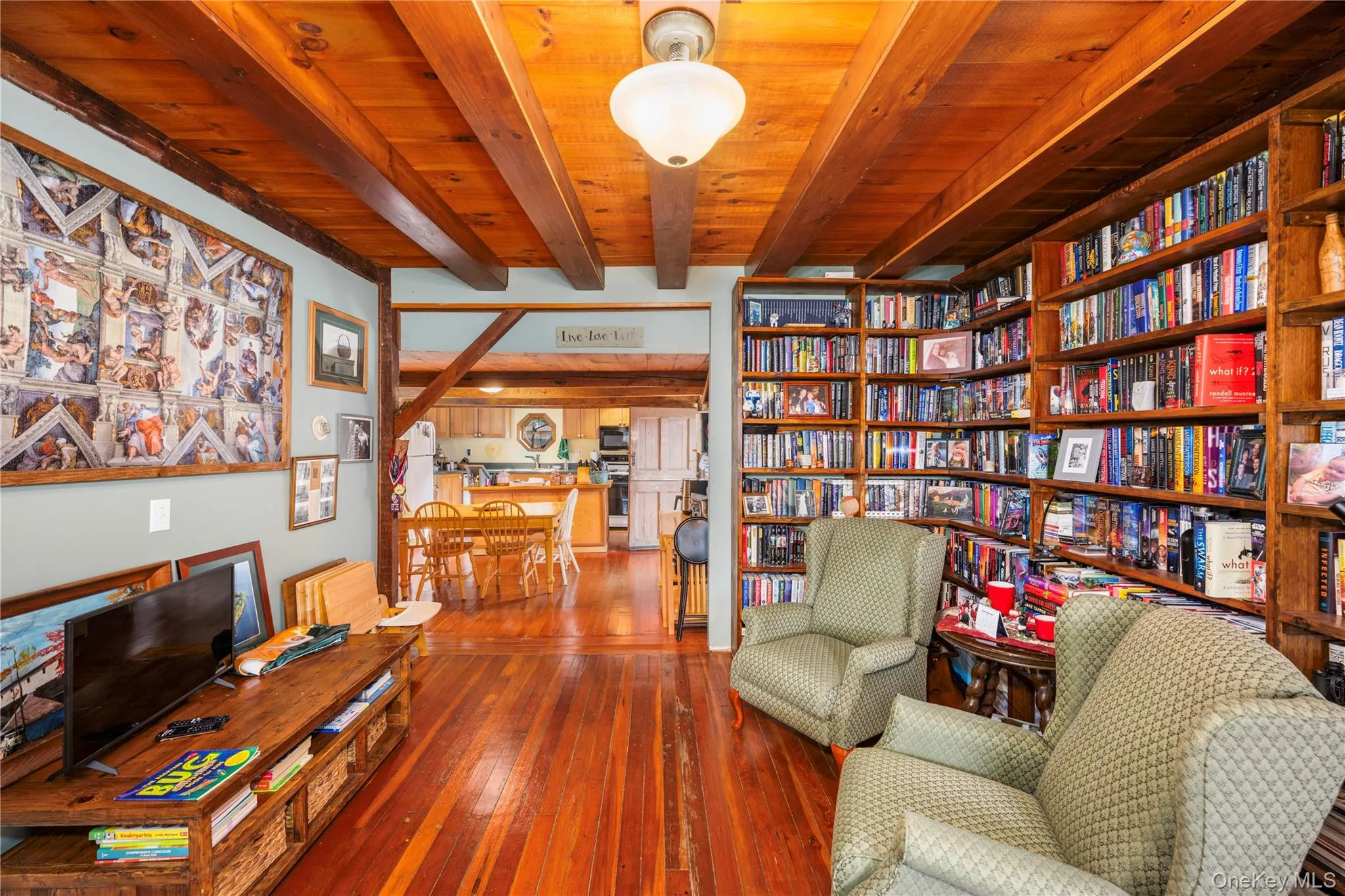 Sitting room featuring beam ceiling, dark wood-type flooring, and bookshelves Sitting room featuring beam ceiling, dark wood-type flooring, and bookshelves
