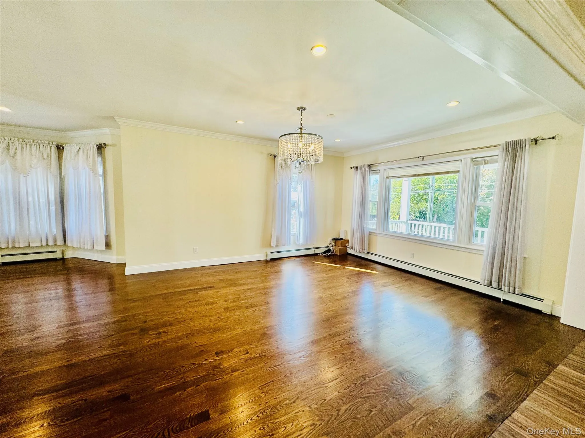 Spare room with crown molding, a baseboard radiator, dark wood-type flooring, a chandelier, and recessed lighting Spare room with crown molding, a baseboard radiator, dark wood-type flooring, a chandelier, and recessed lighting