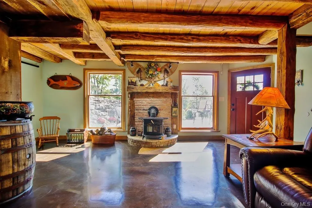 Living area featuring a wood stove, concrete flooring, and a wood ceiling with exposed beams Living area featuring a wood stove, concrete flooring, and a wood ceiling with exposed beams