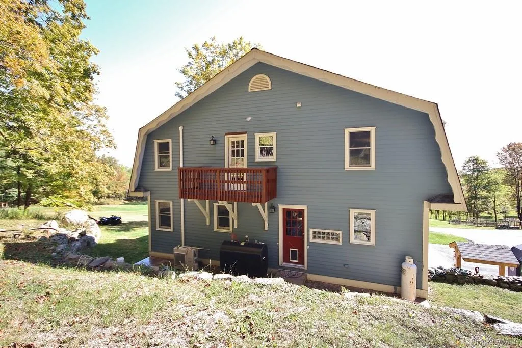Back of house featuring a gambrel roof, a yard, and heating fuel Back of house featuring a gambrel roof, a yard, and heating fuel