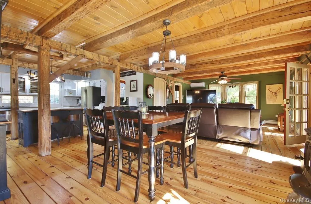 Dining area featuring a ceiling fan, light wood-style floors, a chandelier, and a wood ceiling with exposed beams Dining area featuring a ceiling fan, light wood-style floors, a chandelier, and a wood ceiling with exposed beams