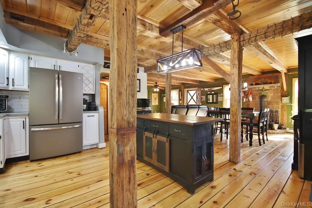 Kitchen featuring freestanding refrigerator, hanging light fixtures, white cabinetry, light wood finished floors, and butcher block counters Kitchen featuring freestanding refrigerator, hanging light fixtures, white cabinetry, light wood finished floors, and butcher block counters