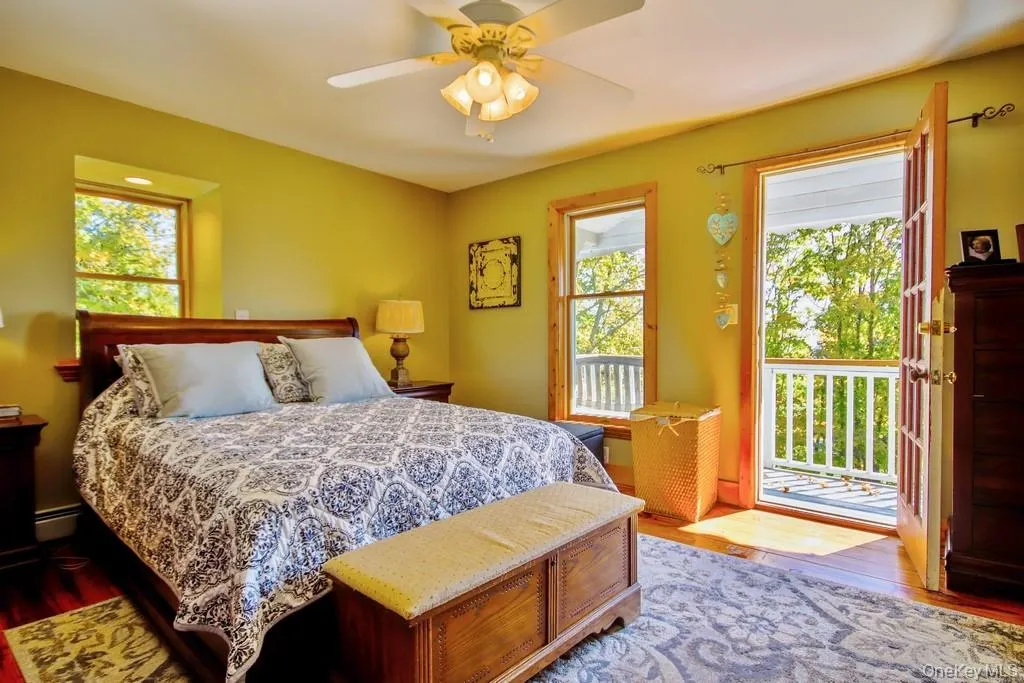 Bedroom featuring wood finished floors, multiple windows, a ceiling fan, and access to outside Bedroom featuring wood finished floors, multiple windows, a ceiling fan, and access to outside