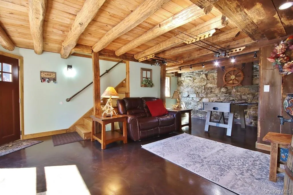 Living area featuring a wood ceiling with exposed beams, stairway, concrete floors, and rail lighting Living area featuring a wood ceiling with exposed beams, stairway, concrete floors, and rail lighting