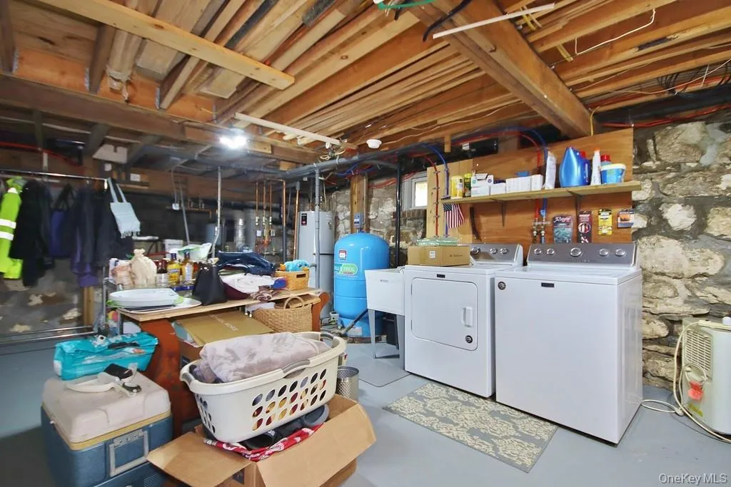 Unfinished basement with a water pressure tank, washing machine and clothes dryer, and water heater Unfinished basement with a water pressure tank, washing machine and clothes dryer, and water heater