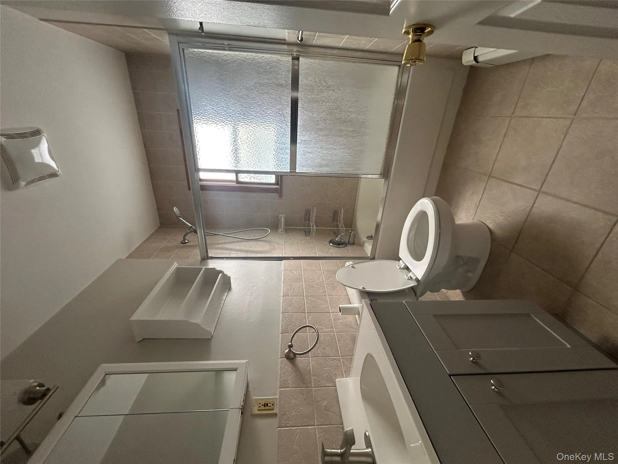 Bathroom featuring combined bath / shower with glass door, vanity, tile walls, and light tile patterned floors Bathroom featuring combined bath / shower with glass door, vanity, tile walls, and light tile patterned floors