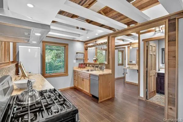 Kitchen featuring ventilation hood, range with gas cooktop, light countertops, dark wood finished floors, and beamed ceiling Kitchen featuring ventilation hood, range with gas cooktop, light countertops, dark wood finished floors, and beamed ceiling