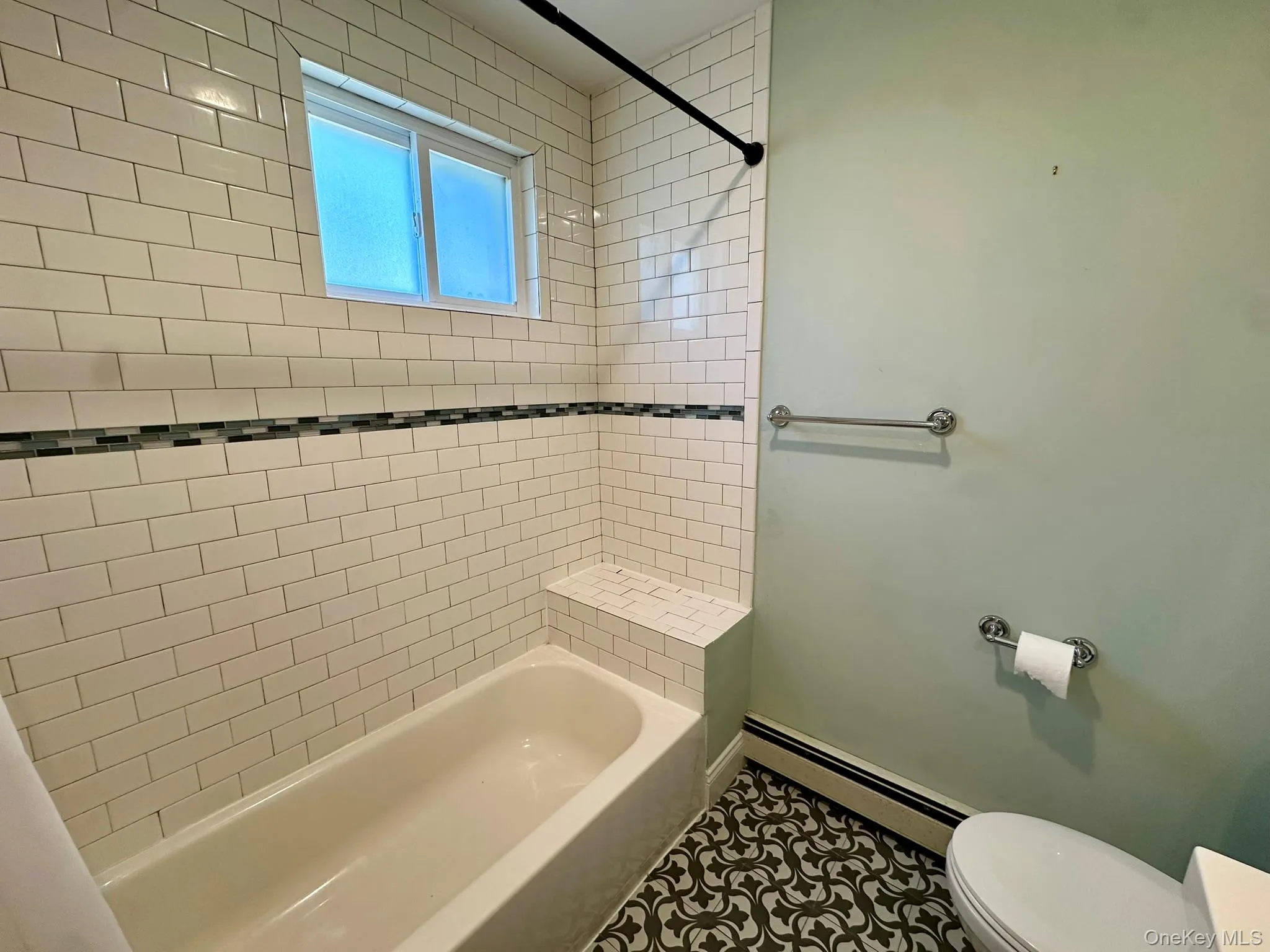 Bathroom featuring baseboard heating, bathtub / shower combination, and tile patterned floors Bathroom featuring baseboard heating, bathtub / shower combination, and tile patterned floors