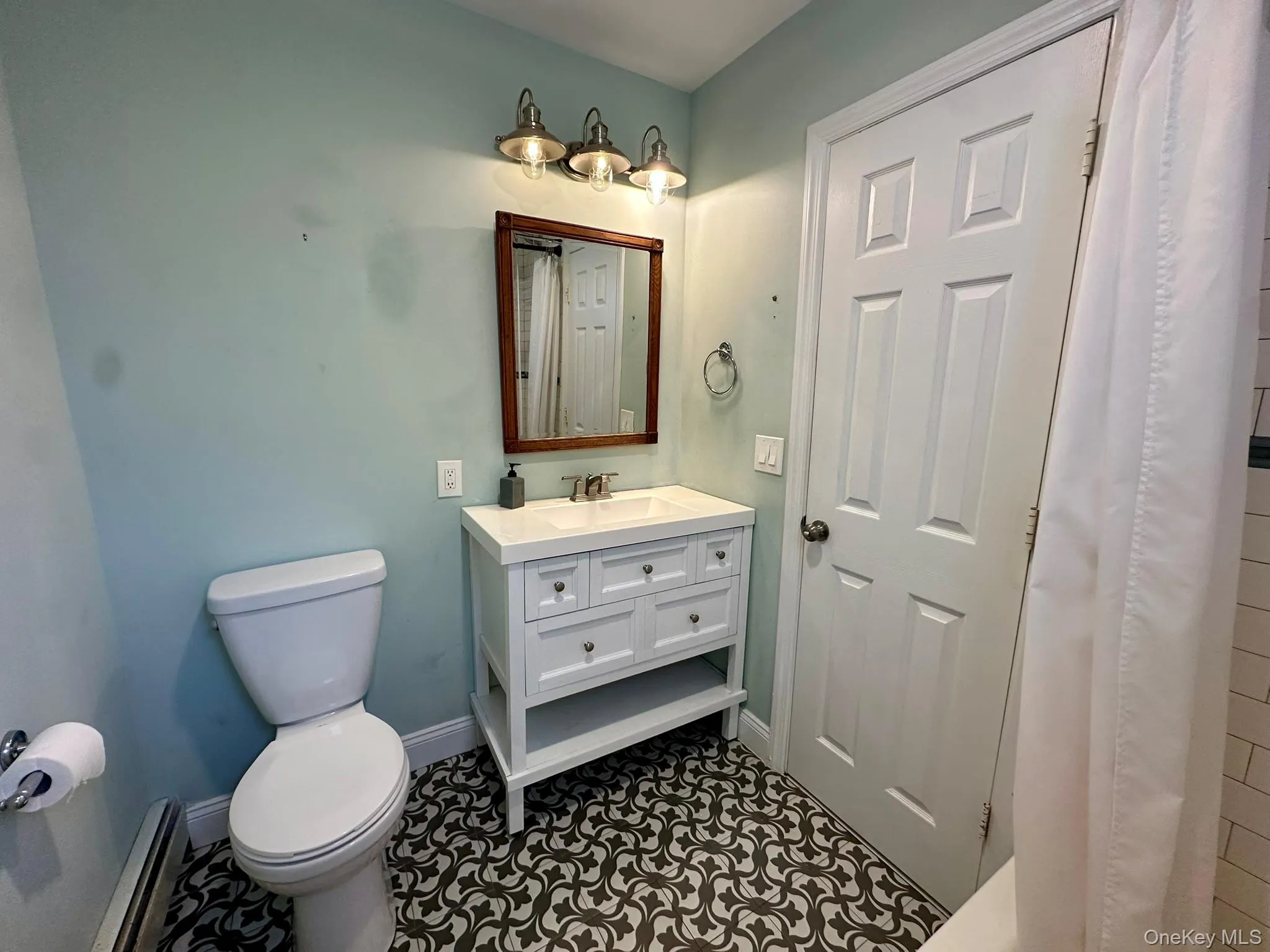 Full bathroom with vanity, baseboard heating, and dark tile patterned floors Full bathroom with vanity, baseboard heating, and dark tile patterned floors