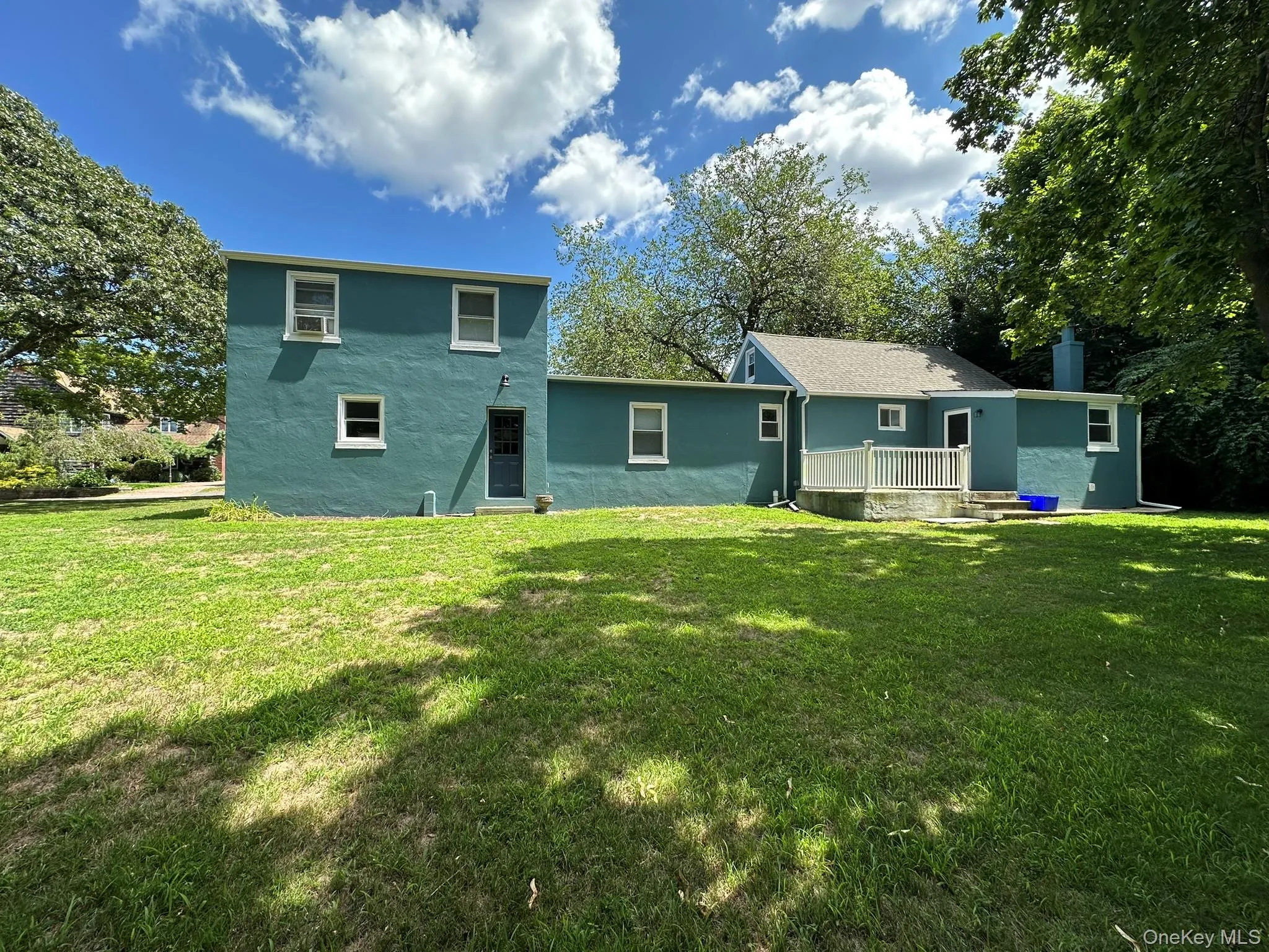 Rear view of house with a lawn, stucco siding, and a chimney Rear view of house with a lawn, stucco siding, and a chimney