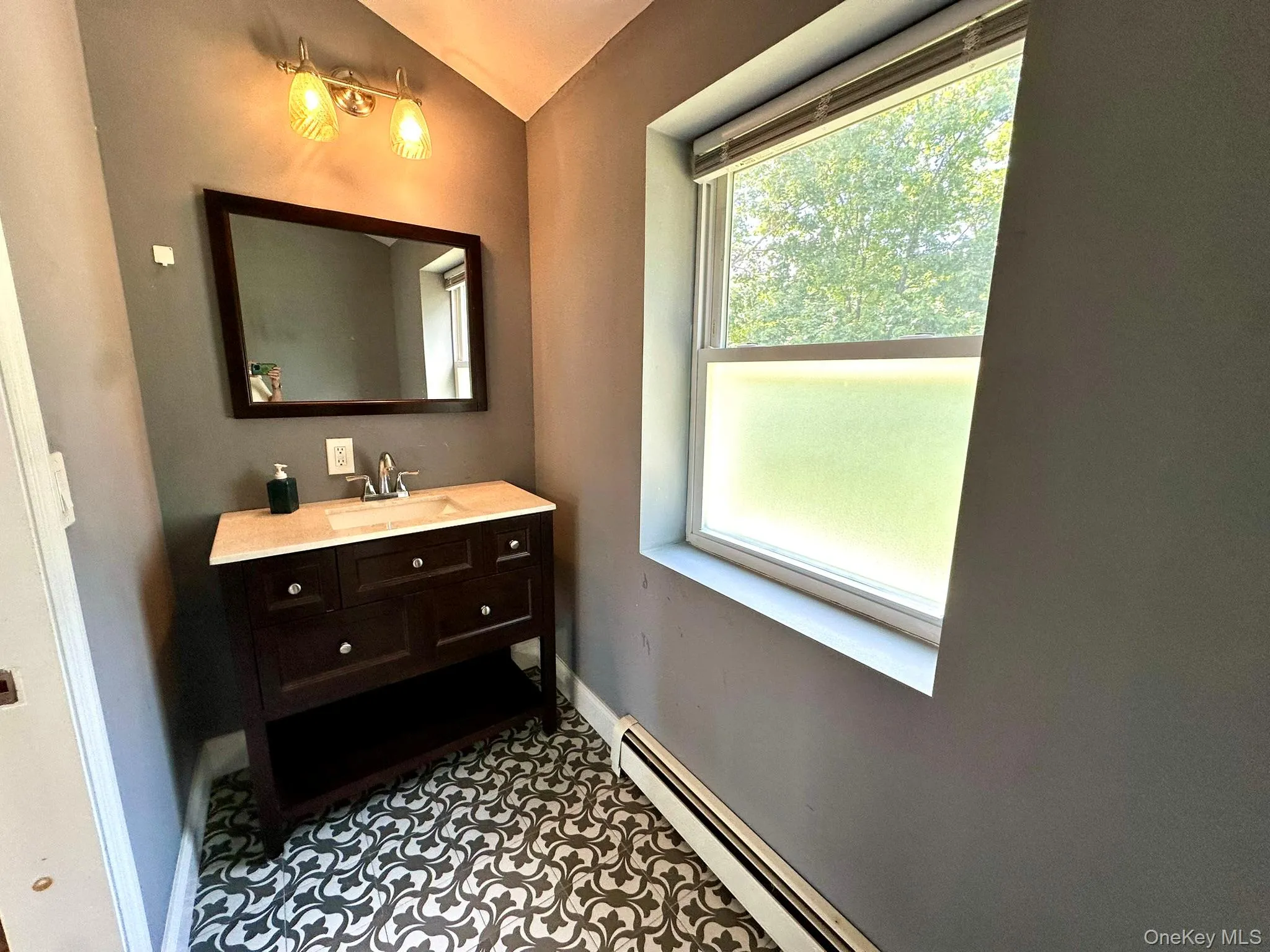 Bathroom featuring a baseboard heating unit, vanity, and dark tile patterned floors Bathroom featuring a baseboard heating unit, vanity, and dark tile patterned floors