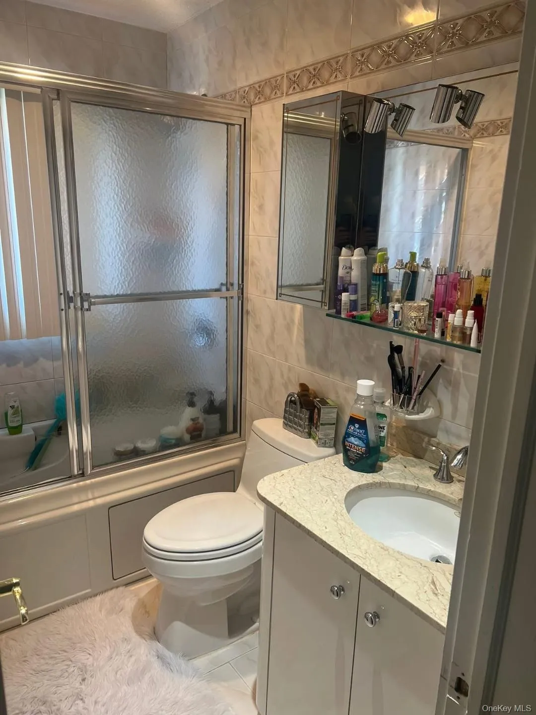 Bathroom featuring combined bath / shower with glass door, tile walls, vanity, light tile patterned flooring, and backsplash Bathroom featuring combined bath / shower with glass door, tile walls, vanity, light tile patterned flooring, and backsplash