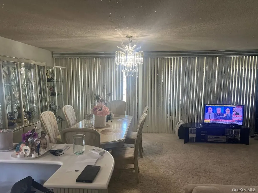 Dining area featuring a textured ceiling, carpet floors, and a chandelier Dining area featuring a textured ceiling, carpet floors, and a chandelier