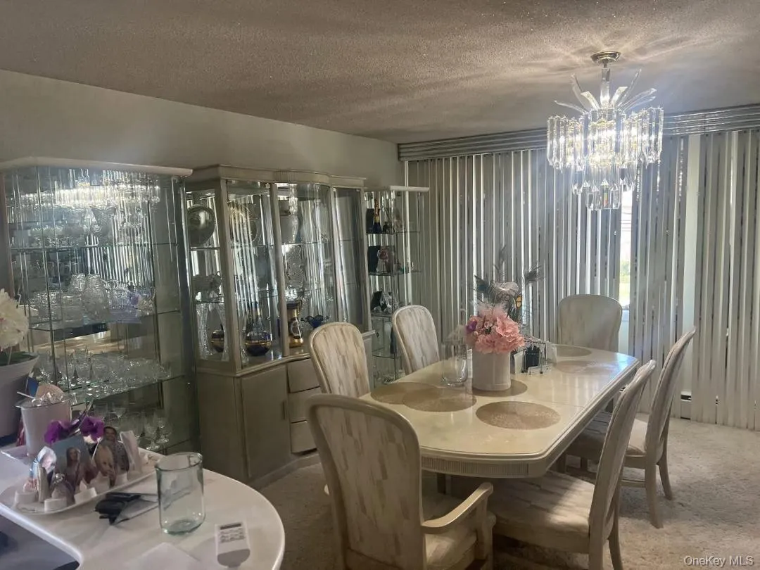 Carpeted dining space with a textured ceiling and a chandelier Carpeted dining space with a textured ceiling and a chandelier