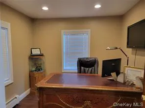 Office space featuring recessed lighting, dark wood-style flooring, and a baseboard heating unit Office space featuring recessed lighting, dark wood-style flooring, and a baseboard heating unit